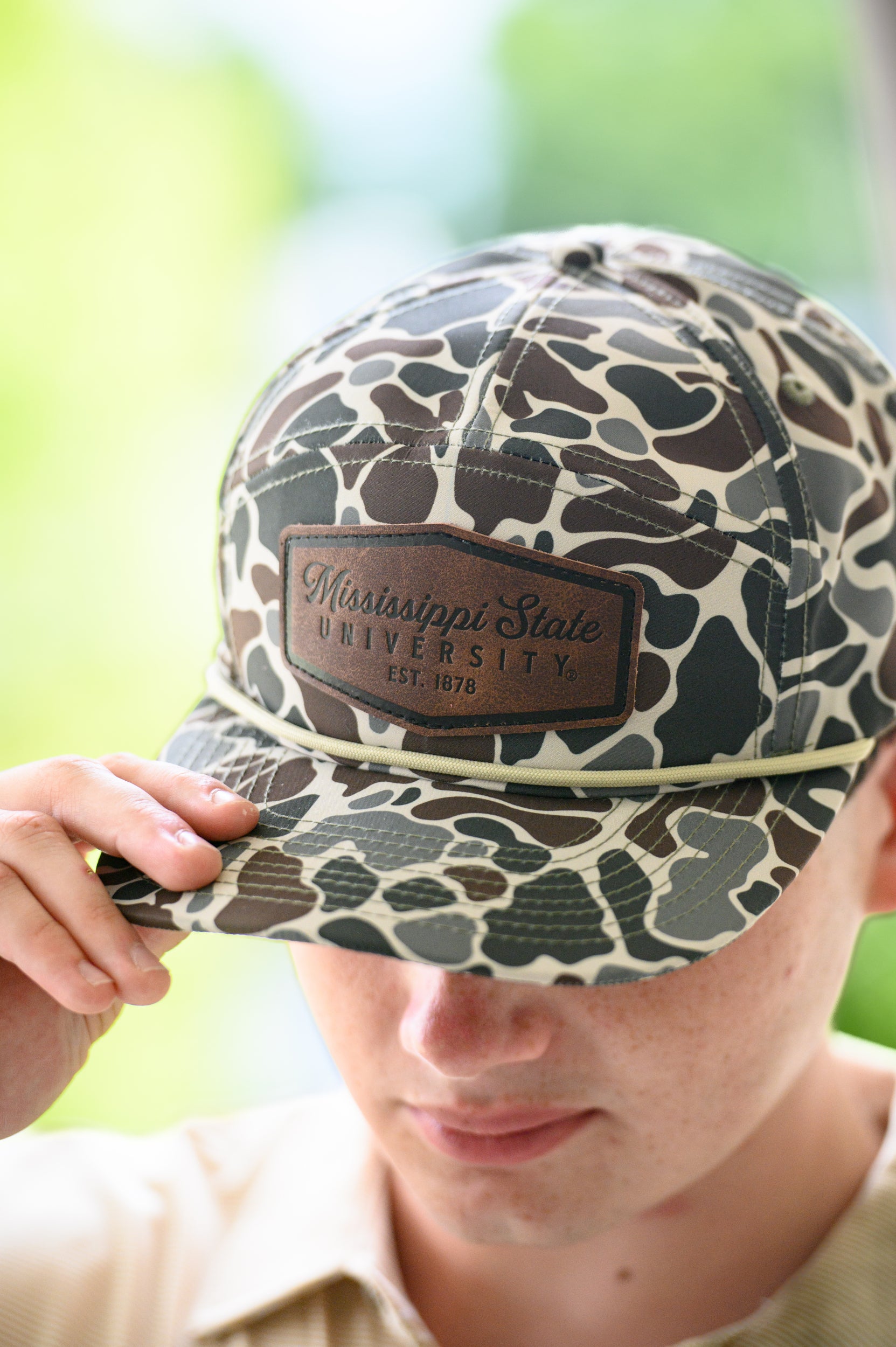 Mississippi State Camo Hat with a White rope and a leather patch with text “Mississippi State University”