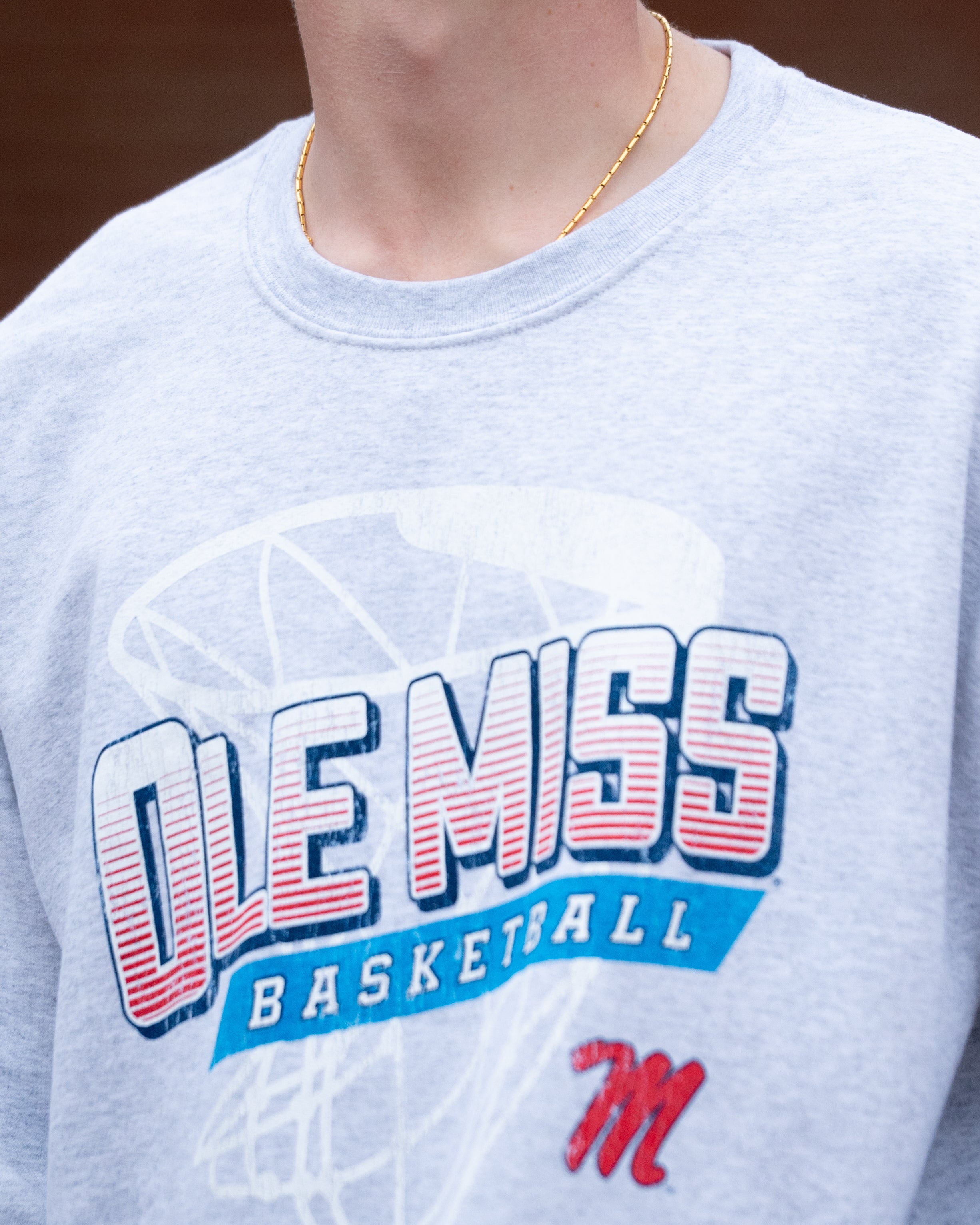 Ole Miss Light Grey Heather Sweatshirt with a basketball hoop outline behind text “Ole Miss Basketball”