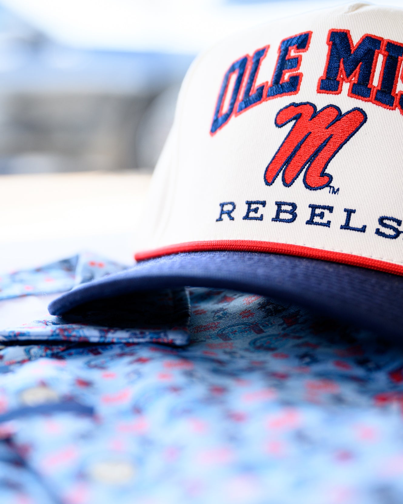 Ole Miss Cream and Navy Hat with embroidered text “Ole Miss Rebels” surrounding the Script M Logo