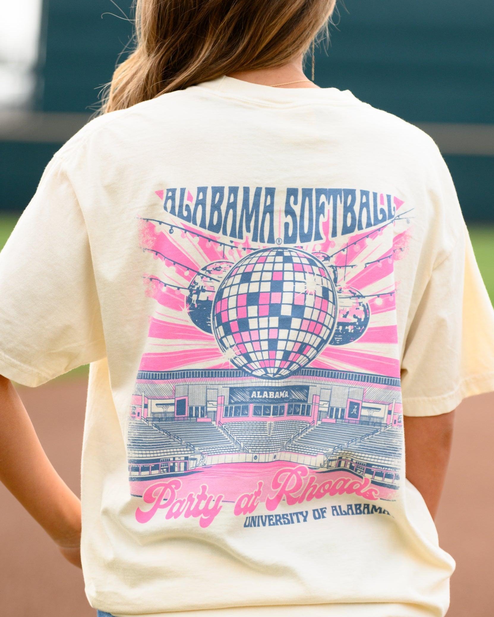 University of Alabama Ivory Ladies' T-Shirt with a hand-drawn design featuring Rhoads Stadium, disco balls, and pink, related to the Alabama Softball team.