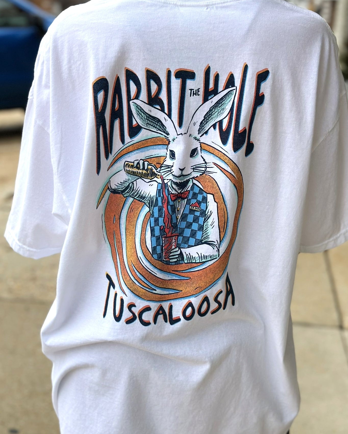 The Rabbit Hole White T-Shirt with an image of The White Rabbit serving a cocktail