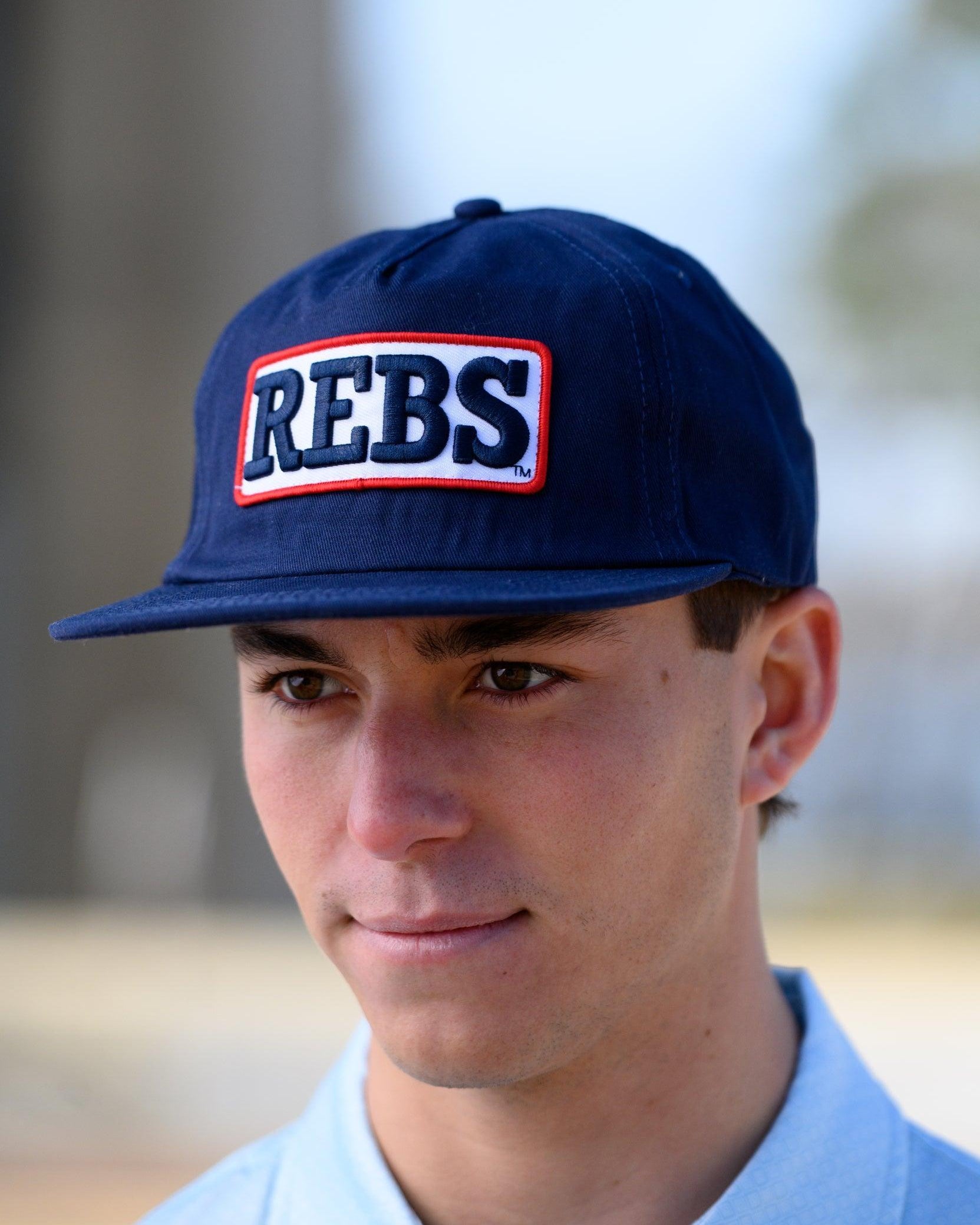 Ole Miss Navy Snapback Hat featuring a White patch with Navy “REBS” embroidery