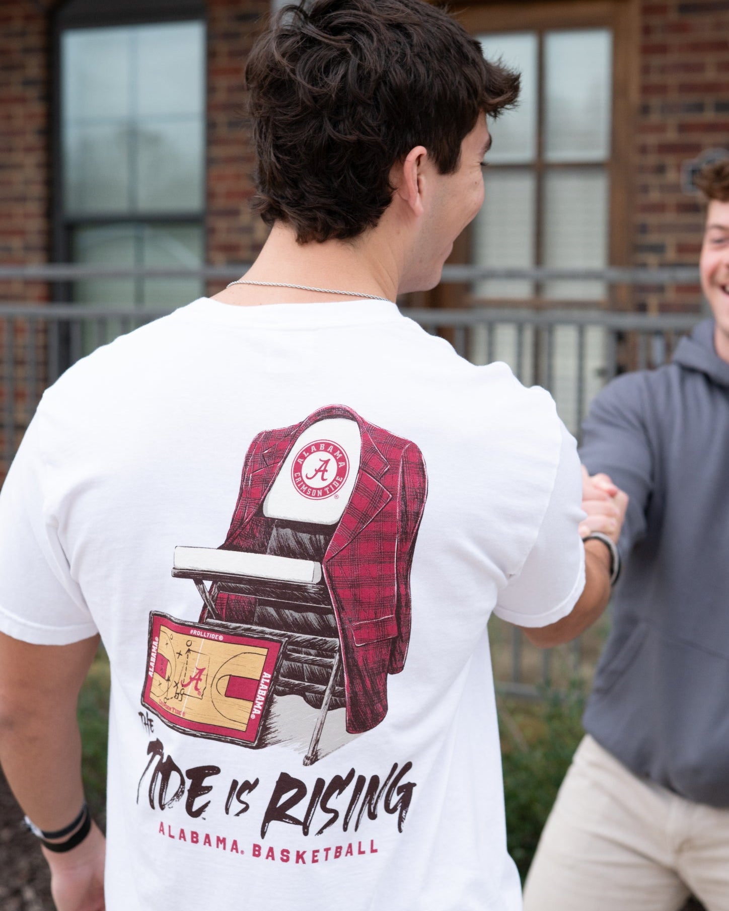 University of Alabama White T-shirt with a Script A brand folding chair that has a red flannel hanging over the back and a play planning board leaning against it. Below, Black text reading “The Tide is Rising”