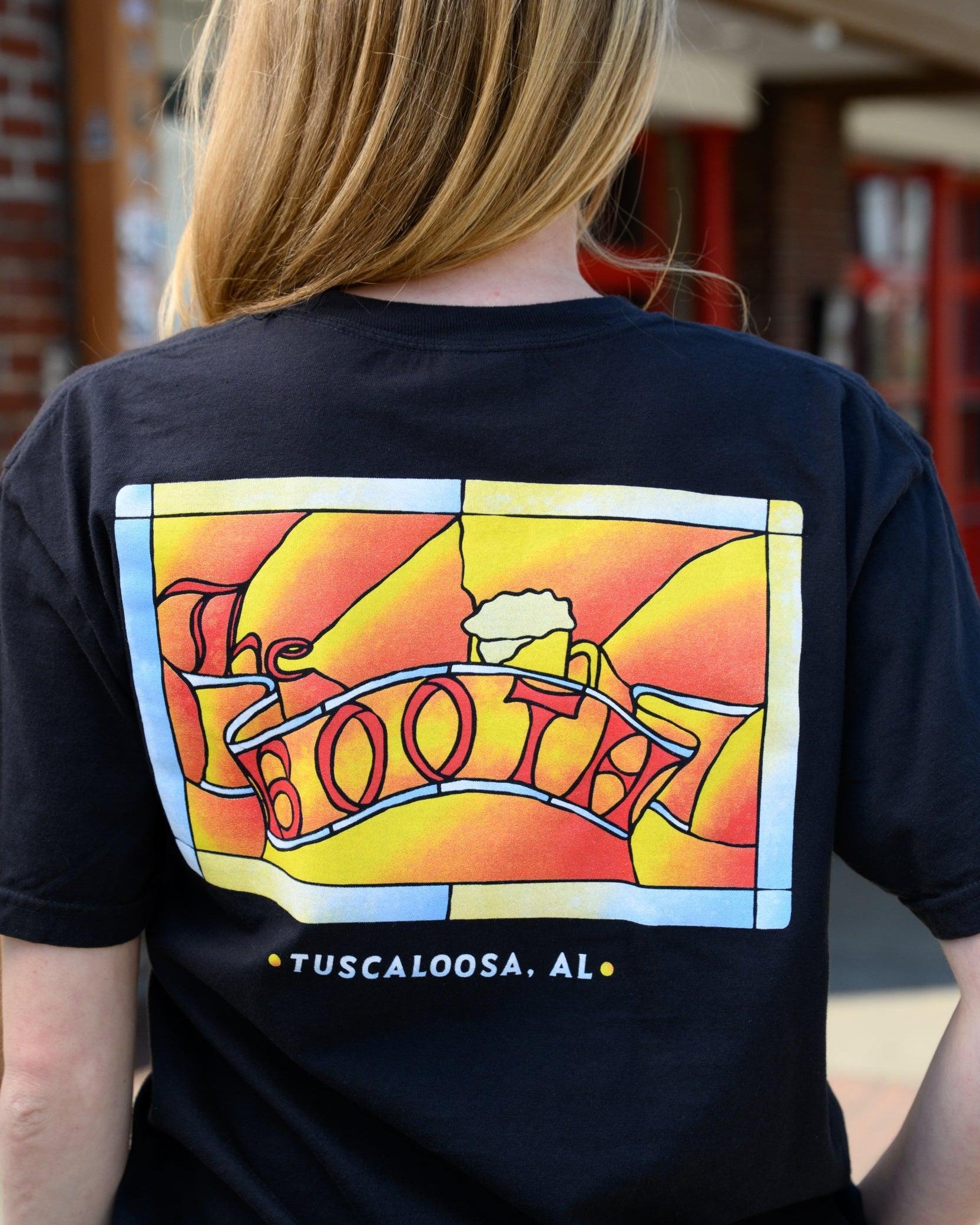 The Booth Black T-Shirt with a stained-glass style graphic featuring a banner with text “The Booth” and a mug of beer