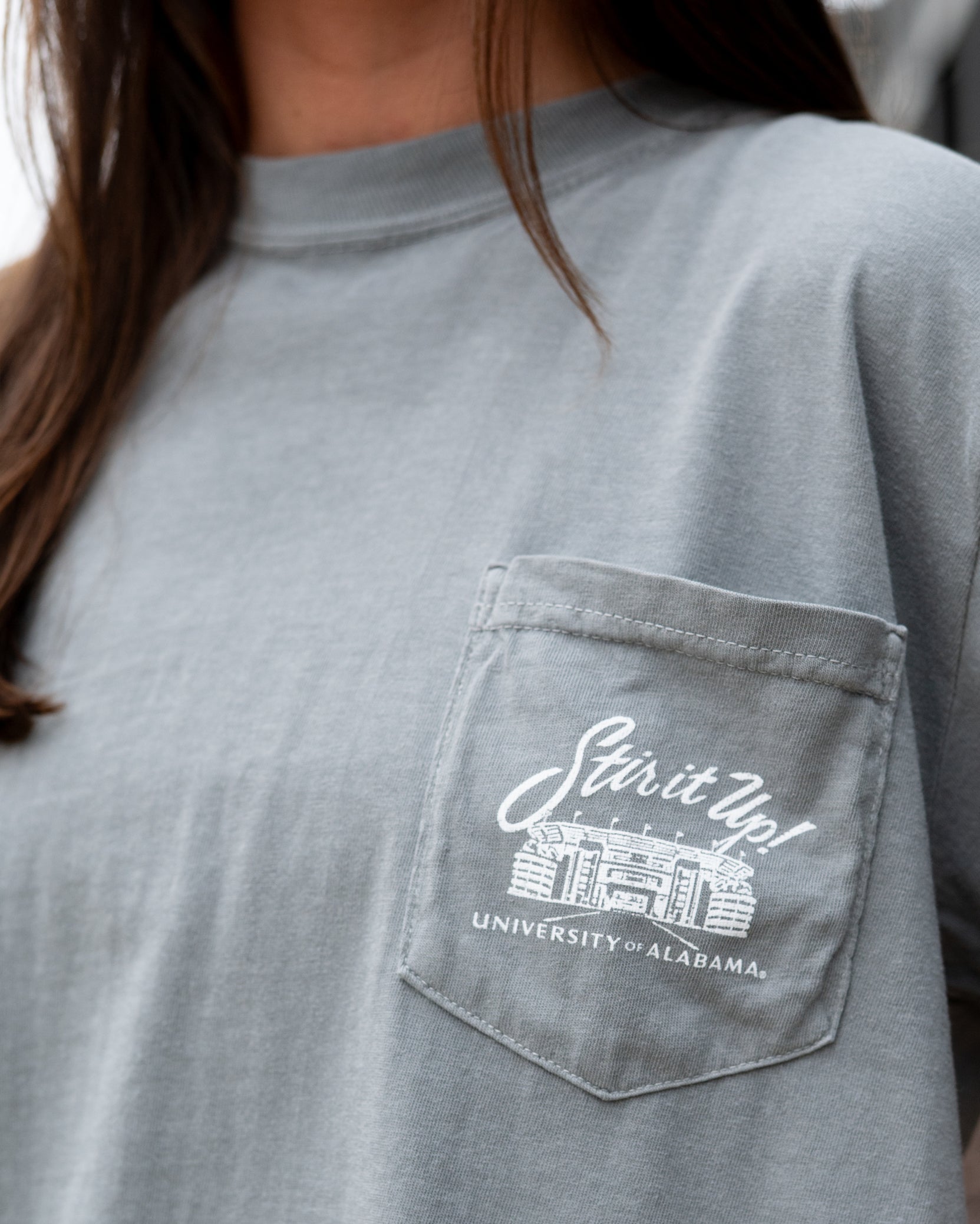 University of Alabama Grey T-Shirt Pocket Design with White text “stir it up” over the Bryant-Denny Stadium