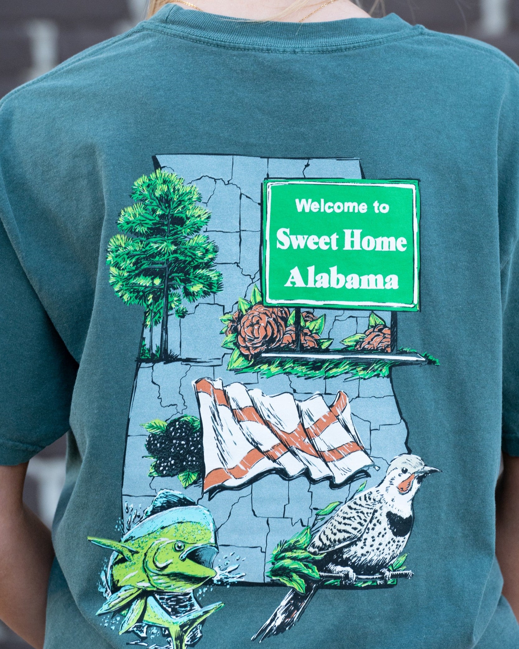 Blue Spruce Sweet Home Alabama T-Shirt with a graphic design that includes the state bird, flag, flower, and other elements representing Alabama.