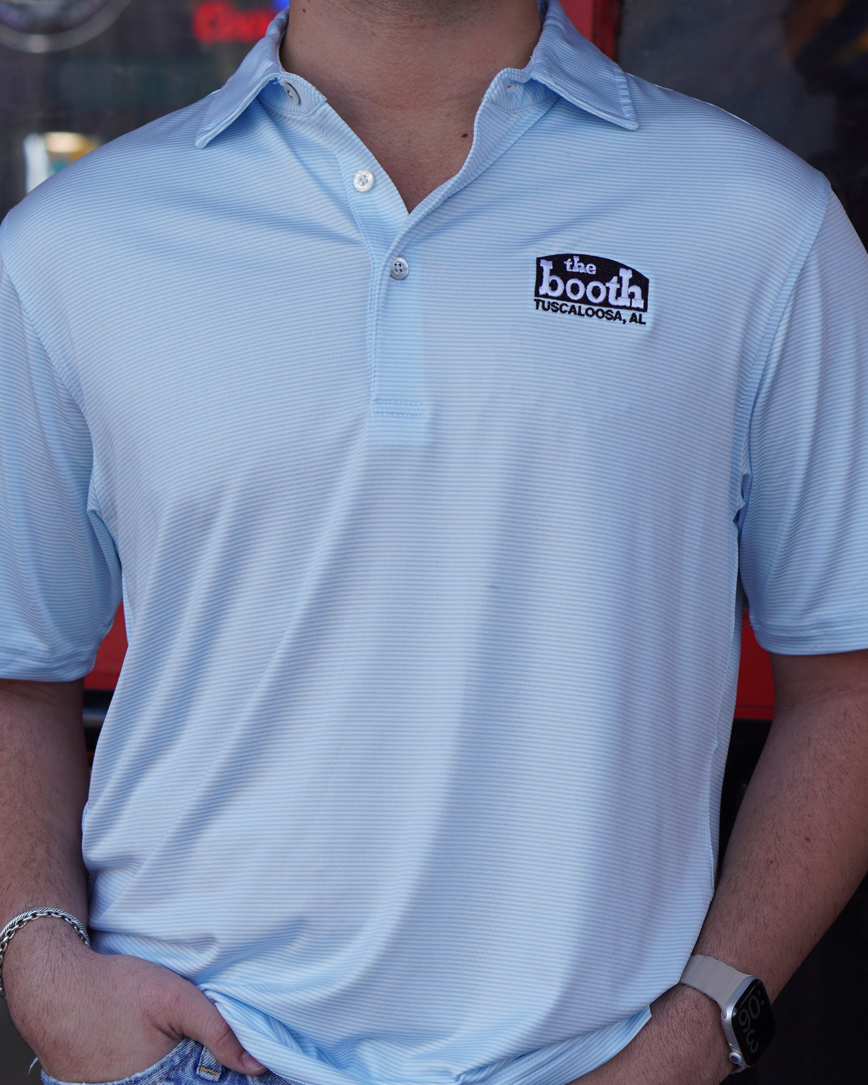 The Booth Light Blue Stripe Men’s Polo with The Booth Logo embroidered on the chest