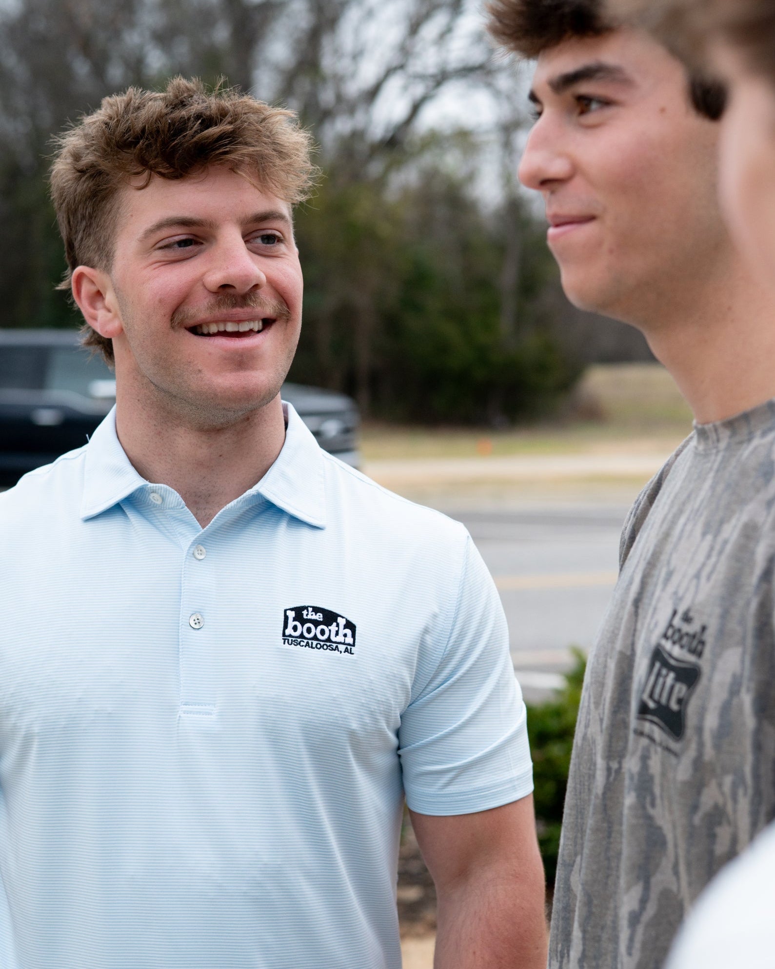The Booth Light Blue Stripe Men’s Polo with The Booth Logo embroidered on the chest