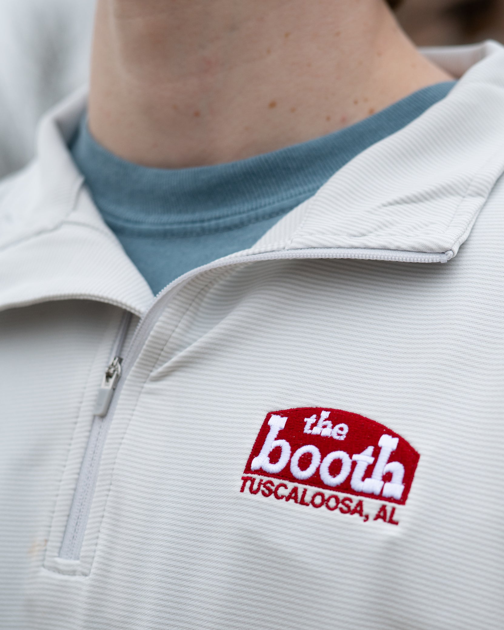 The Booth Light Blue Stripe Men’s Pullover with a Red The Booth Logo embroidered on the chest