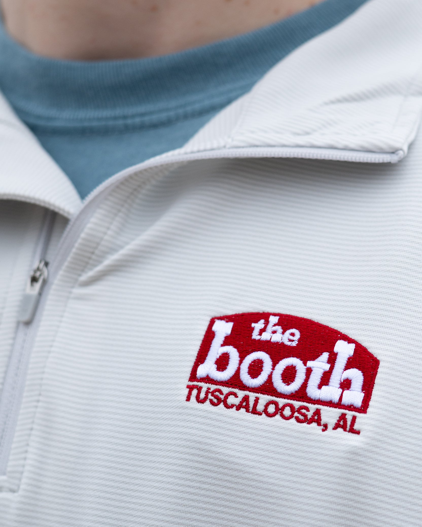 The Booth Light Blue Stripe Men’s Pullover with a Red The Booth Logo embroidered on the chest