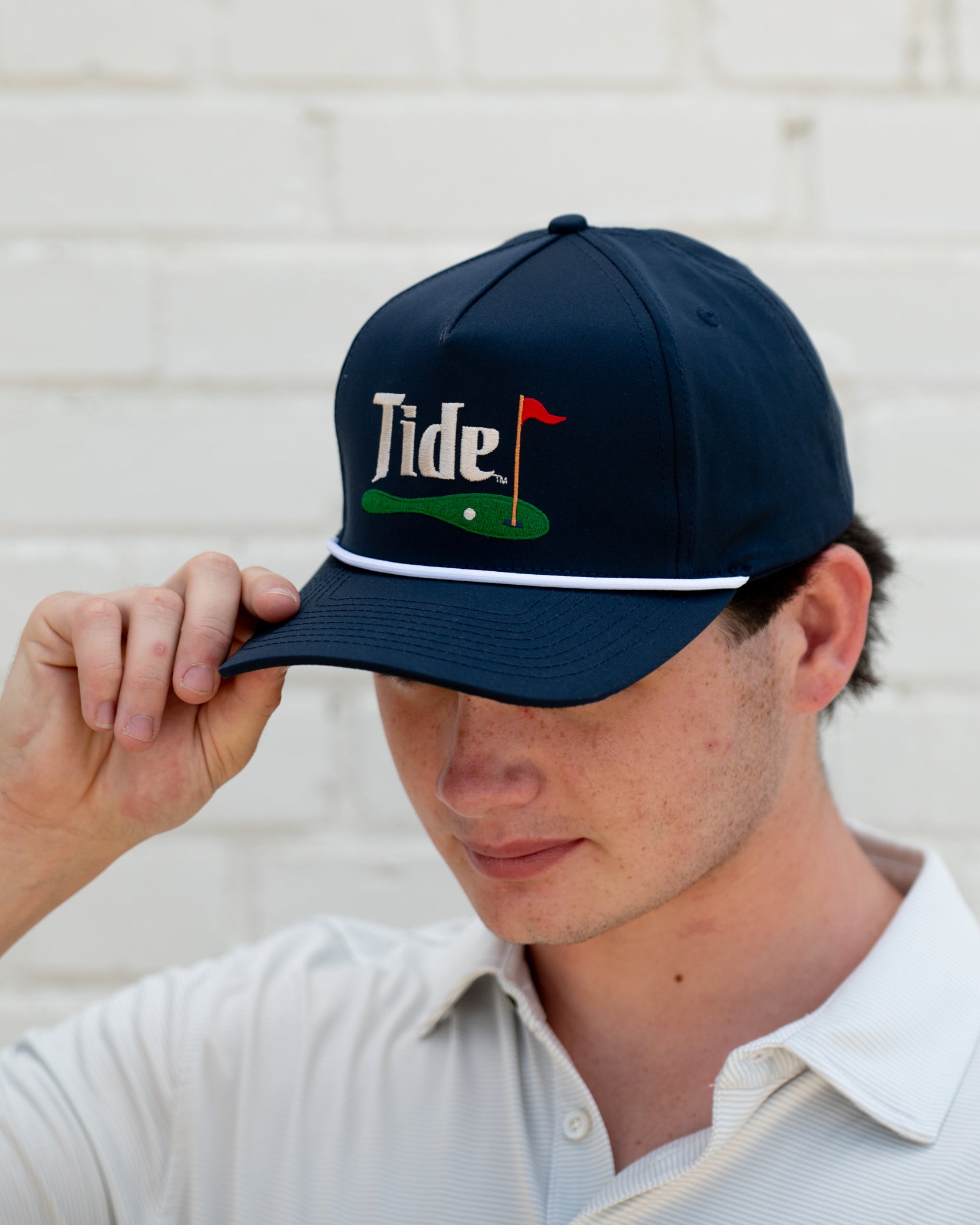 University of Alabama Navy Hat with a White Rope and White text “Tide” above an image of a golf hole