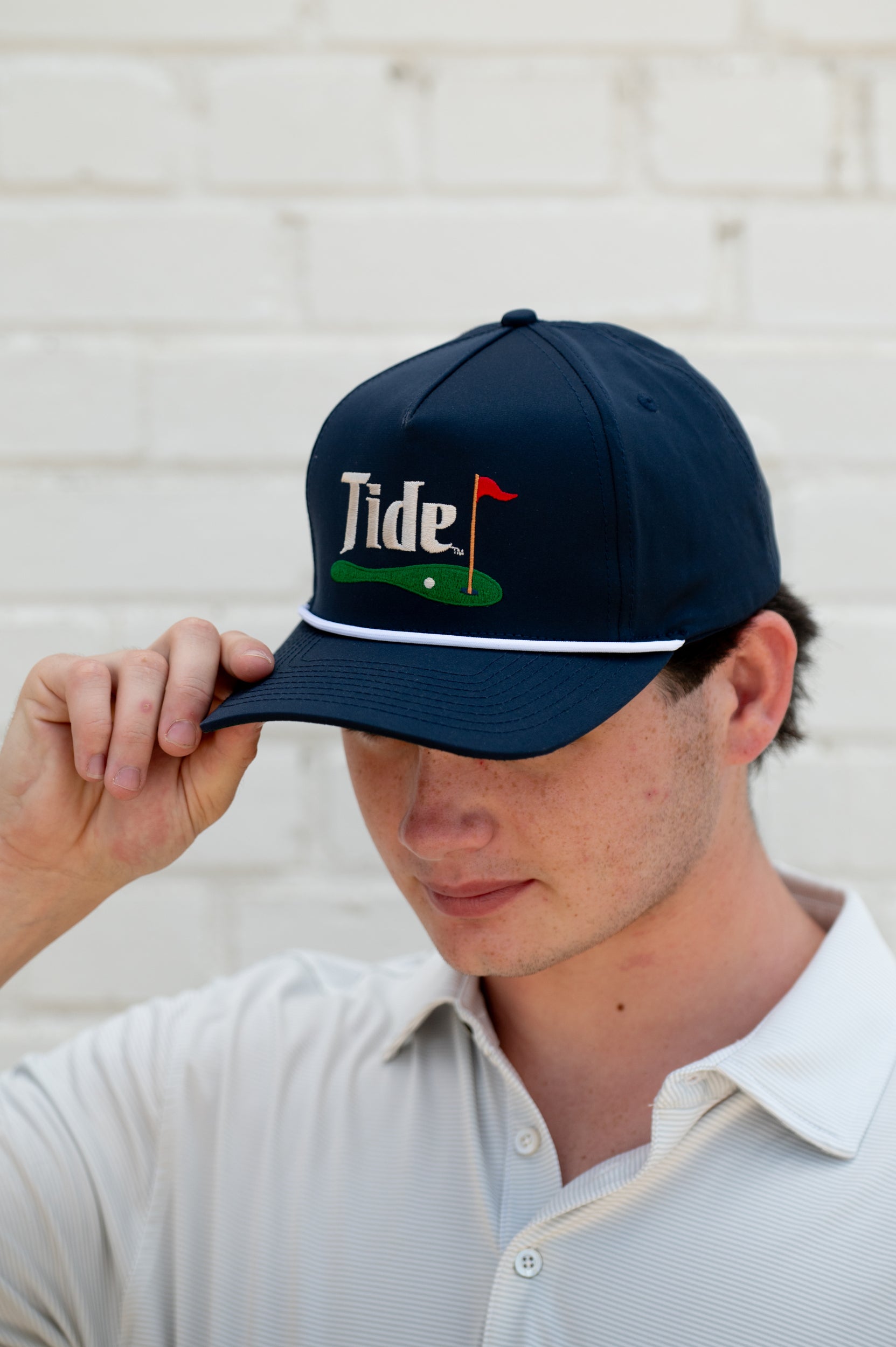 University of Alabama Navy Hat with a White Rope and White text “Tide” above an image of a golf hole