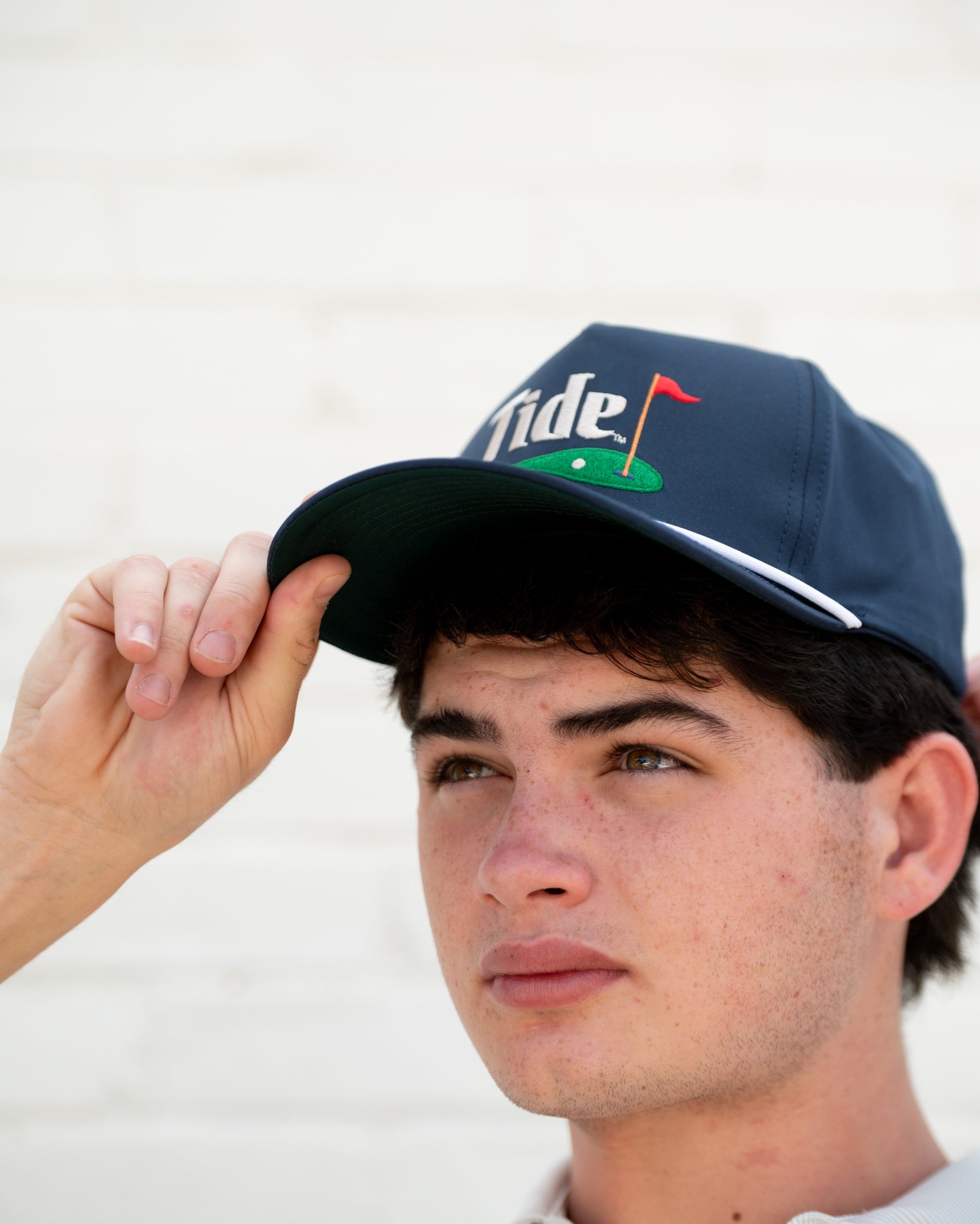 University of Alabama Navy Hat with a White Rope and White text “Tide” above an image of a golf hole