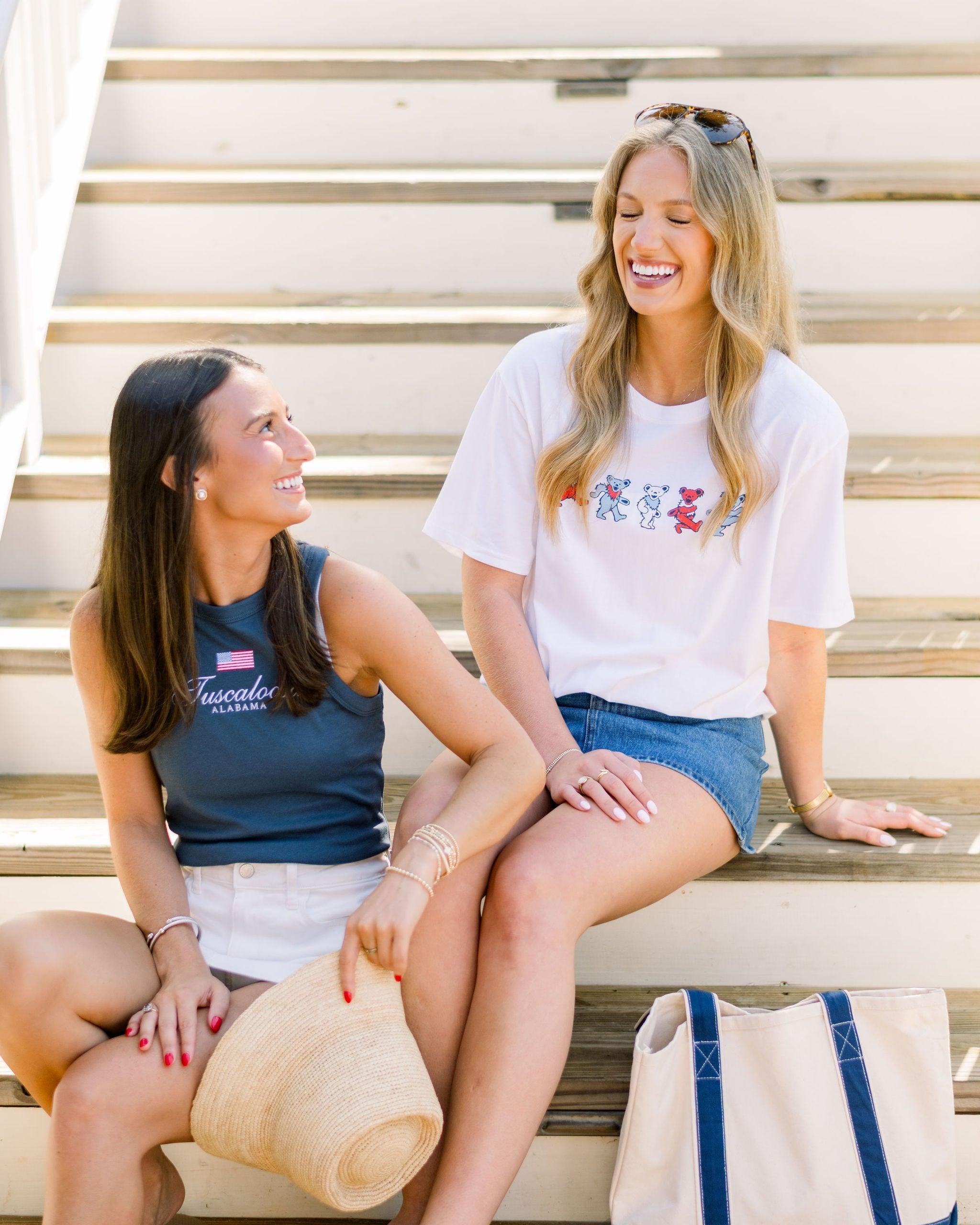 Two women sitting together, one in the Tuscaloosa Americana Tank, the other in the Patriotic Bears T-Shirt