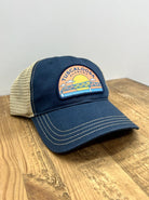 Tuscaloosa Navy and Beige Trucker Hat with a patch featuring Blue text "Tuscaloosa Alabama" a drawing of the sun setting on the iconic Tuscaloosa Railroad Tracks