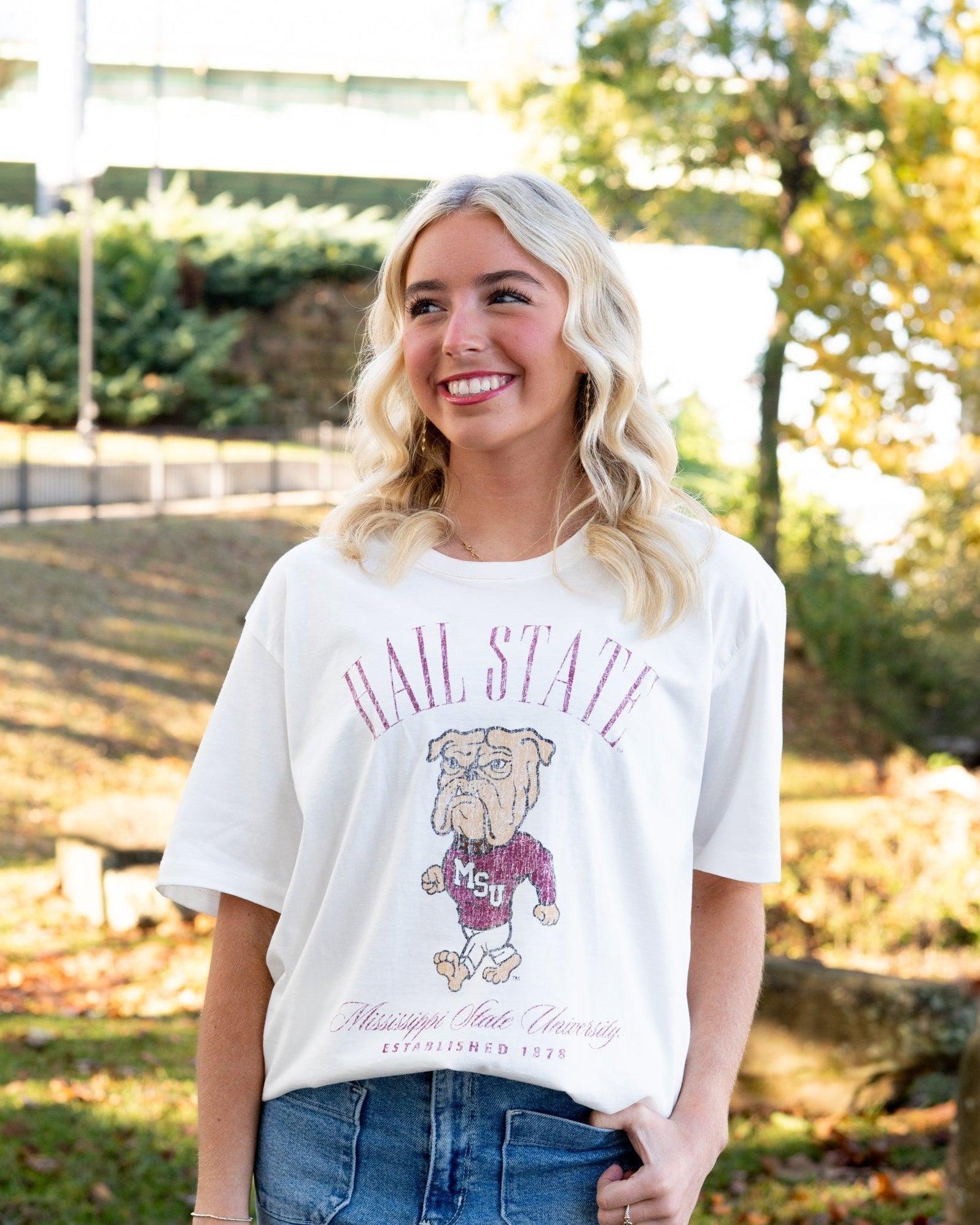 Mississippi State Ivory T-Shirt with Red text “Hail State” above an image of the Walking Bully Logo