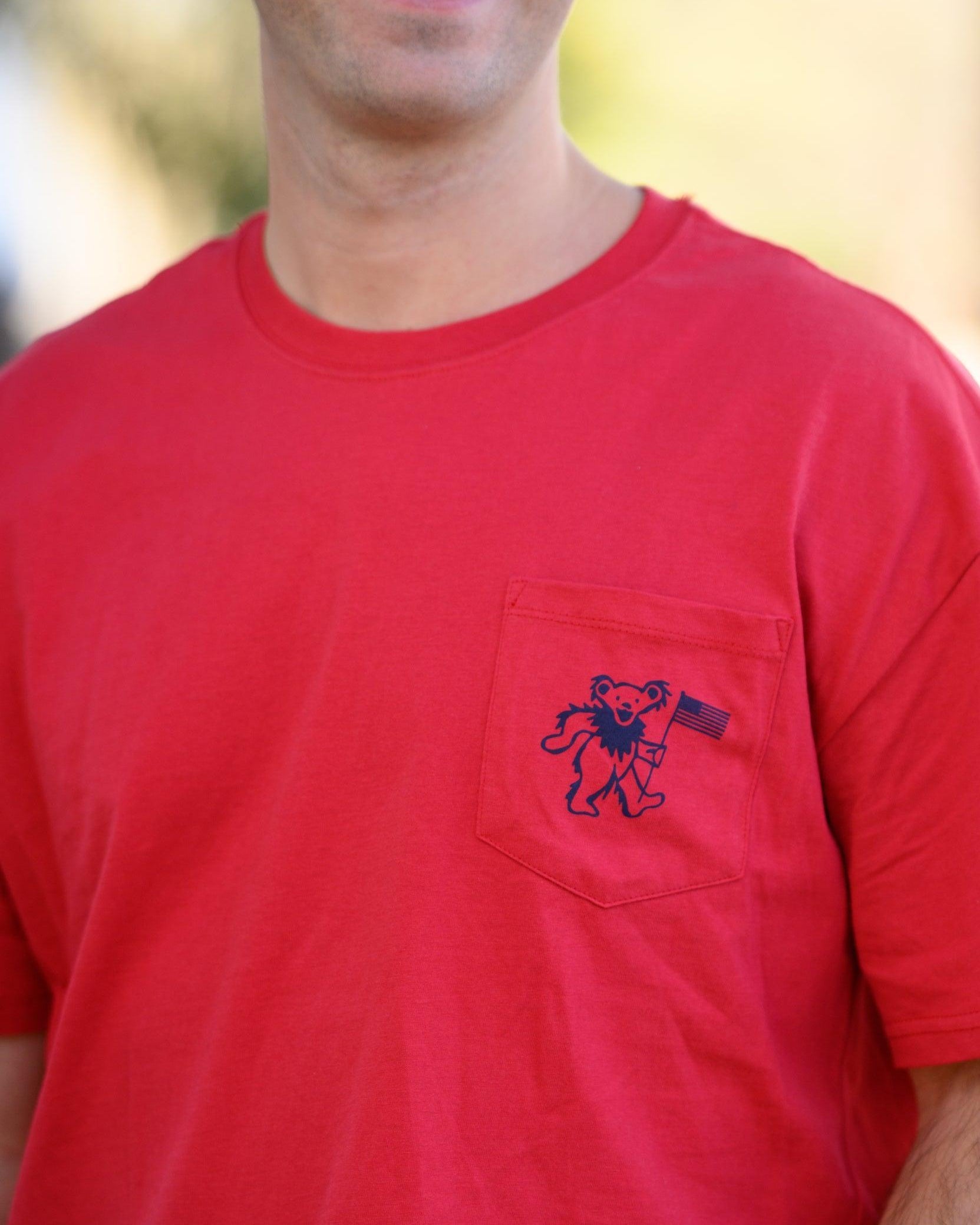 Grateful State Red T-Shirt with a front pocket design featuring a dancing bear holding a flag