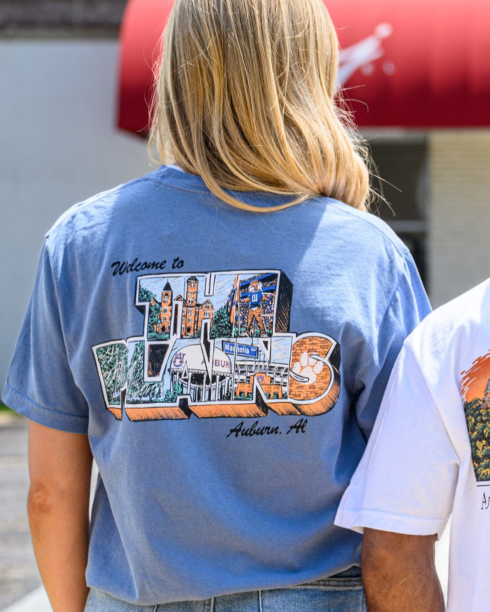 Auburn University Blue The Plains T-Shirt with postcard style text "Welcome to THE PLAINS" with "The Plains" filled with images of iconic buildings in that location