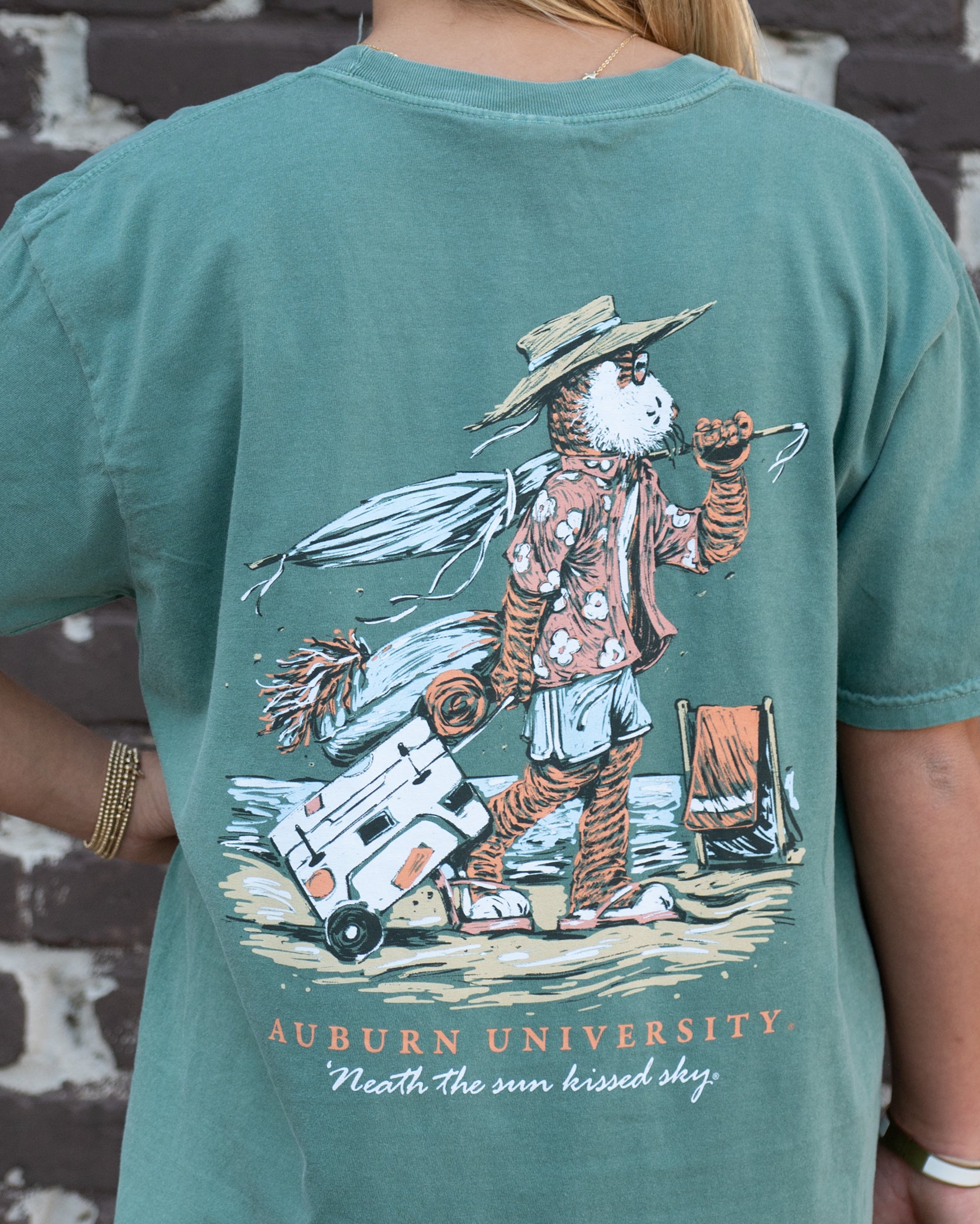 Auburn University Aubie Beach Green Comfort Colors T-Shirt with an image of Aubie the Tiger in beach clothes carrying an umbrella dragging a cooler across the sand