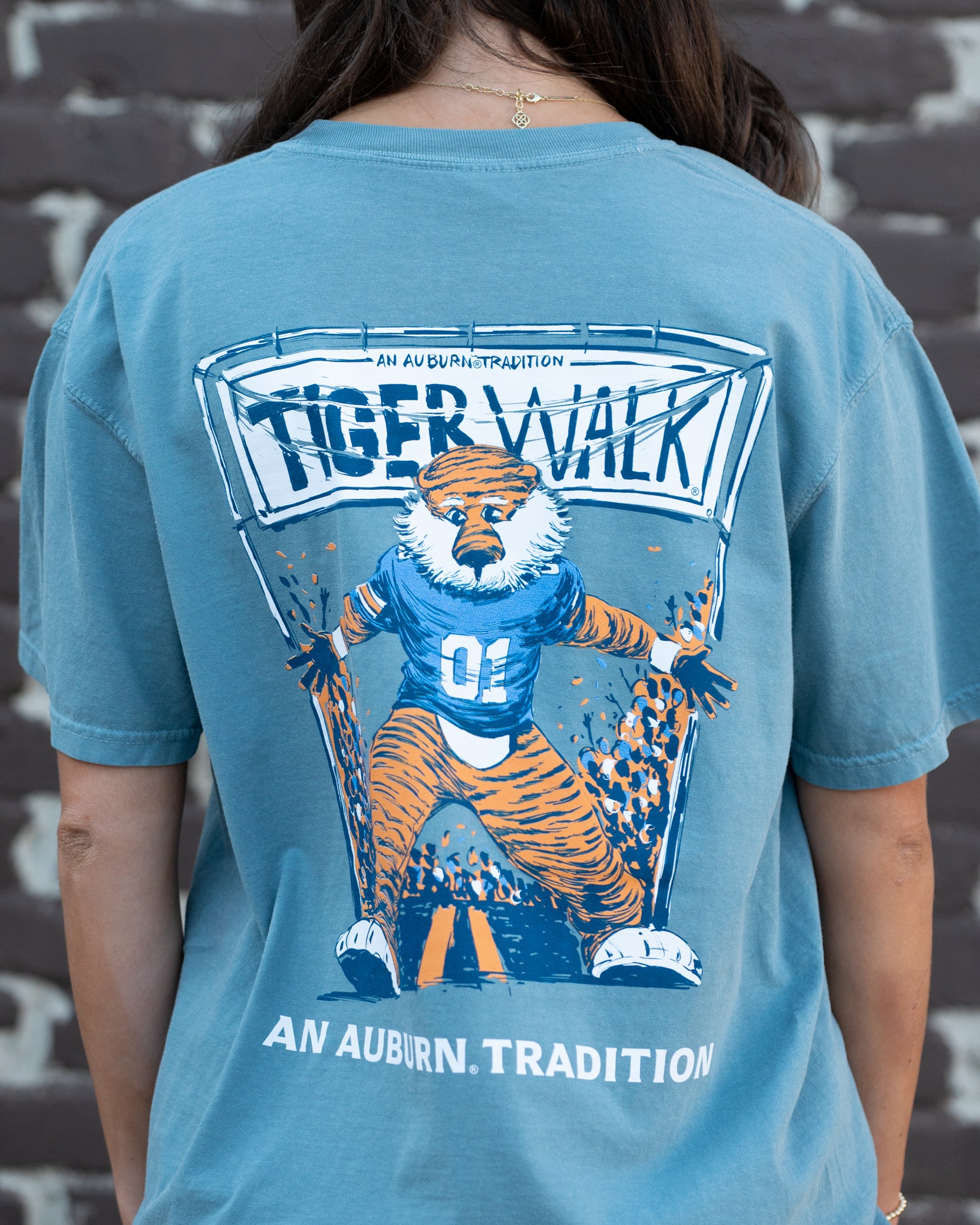 Auburn University Aubie Tiger Walk Ice Blue Comfort Colors T-Shirt with an image of Aubie the Tiger leading a parade under a banner with the text "Tiger Walk"