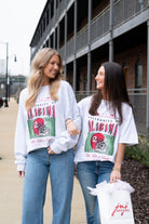 Two women wearing University of Alabama sweatshirts standing outdoors.