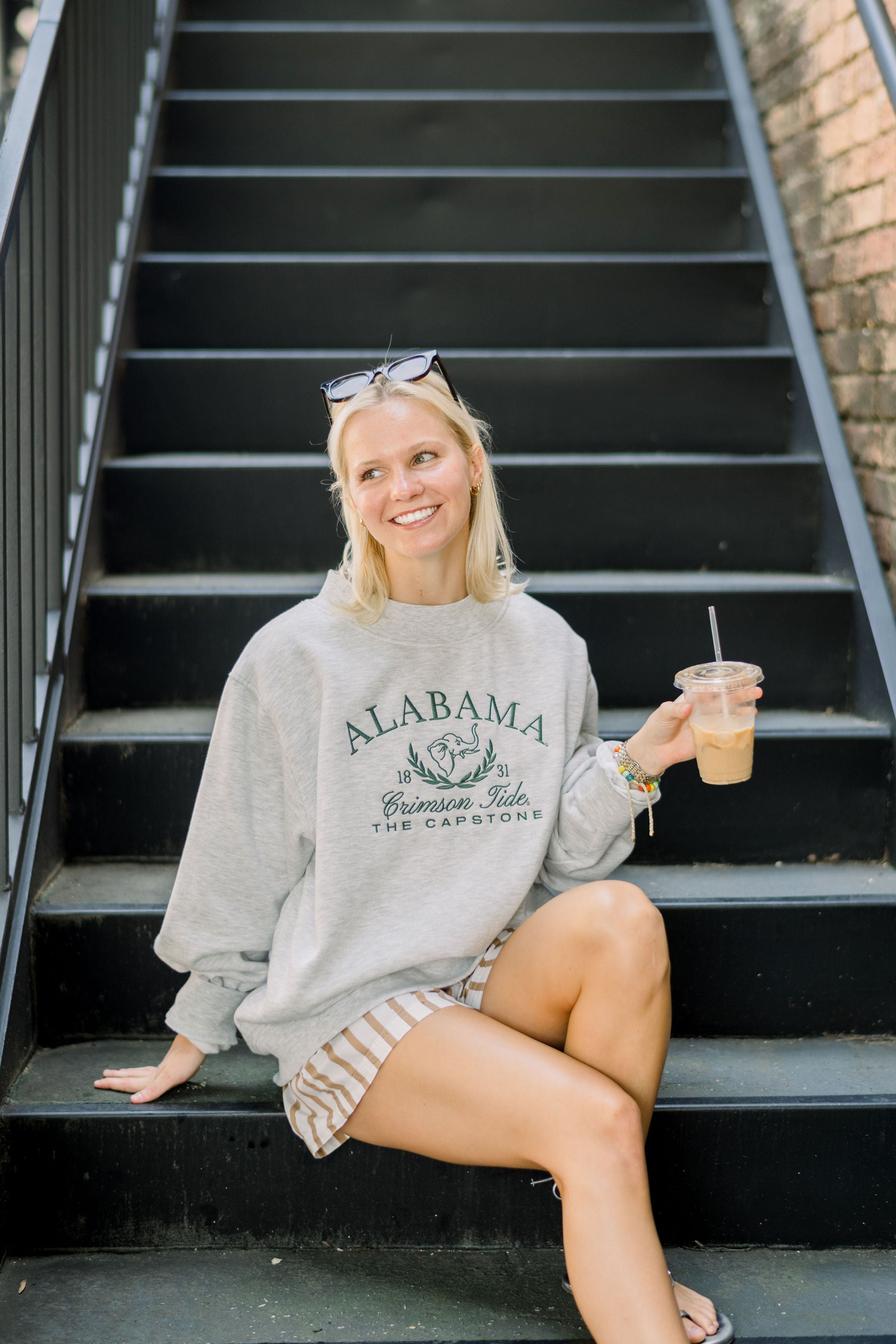 University of Alabama Grey Mock Neck Sweatshirt with Green Embroidered text “Alabama” above the elephant crest (An elephant head outline encircled by a wreath of laurels), and text “Crimson Tide- The Capstone”