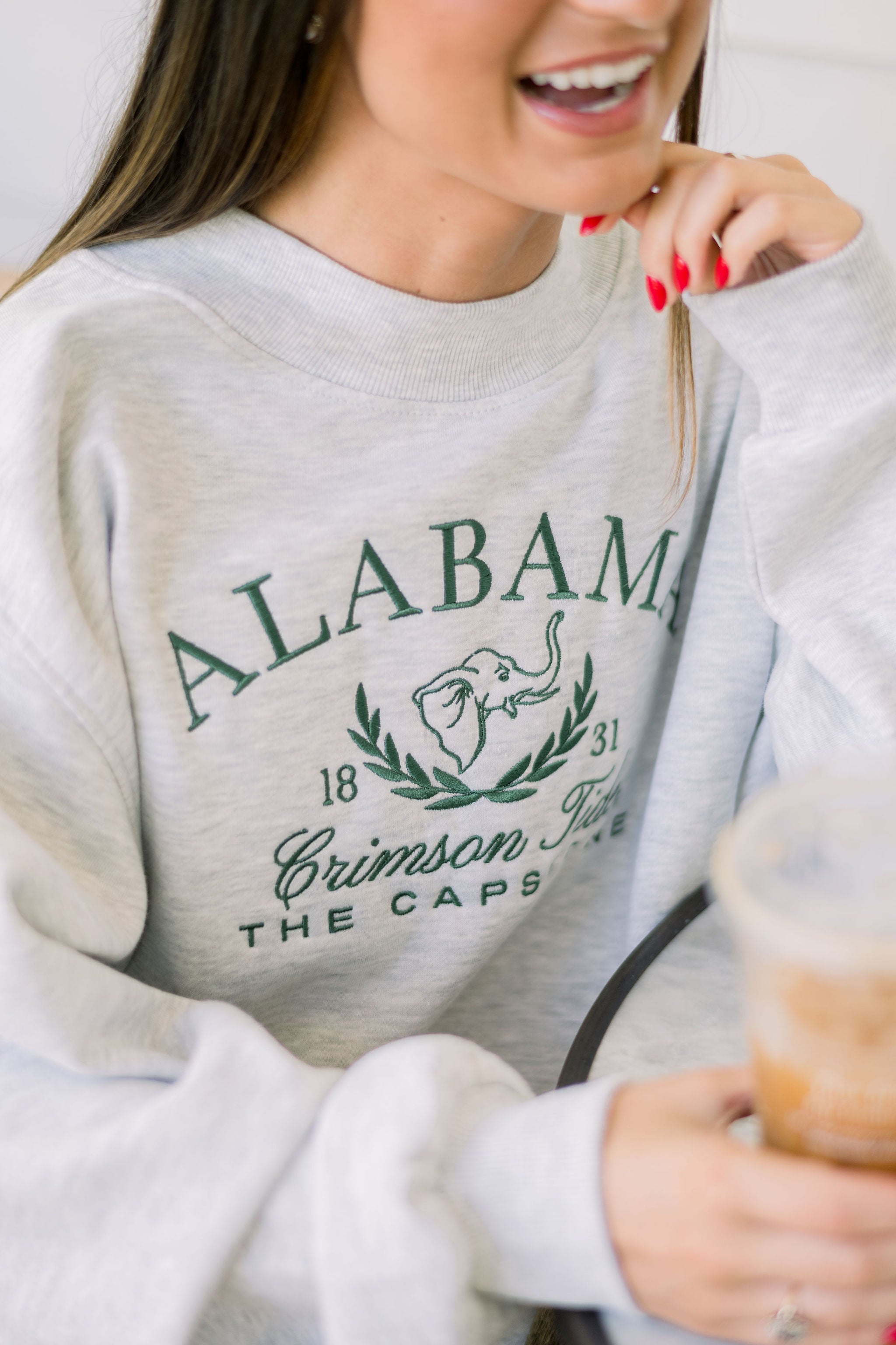University of Alabama Grey Mock Neck Sweatshirt with Green Embroidered text “Alabama” above the elephant crest (An elephant head outline encircled by a wreath of laurels), and text “Crimson Tide- The Capstone”