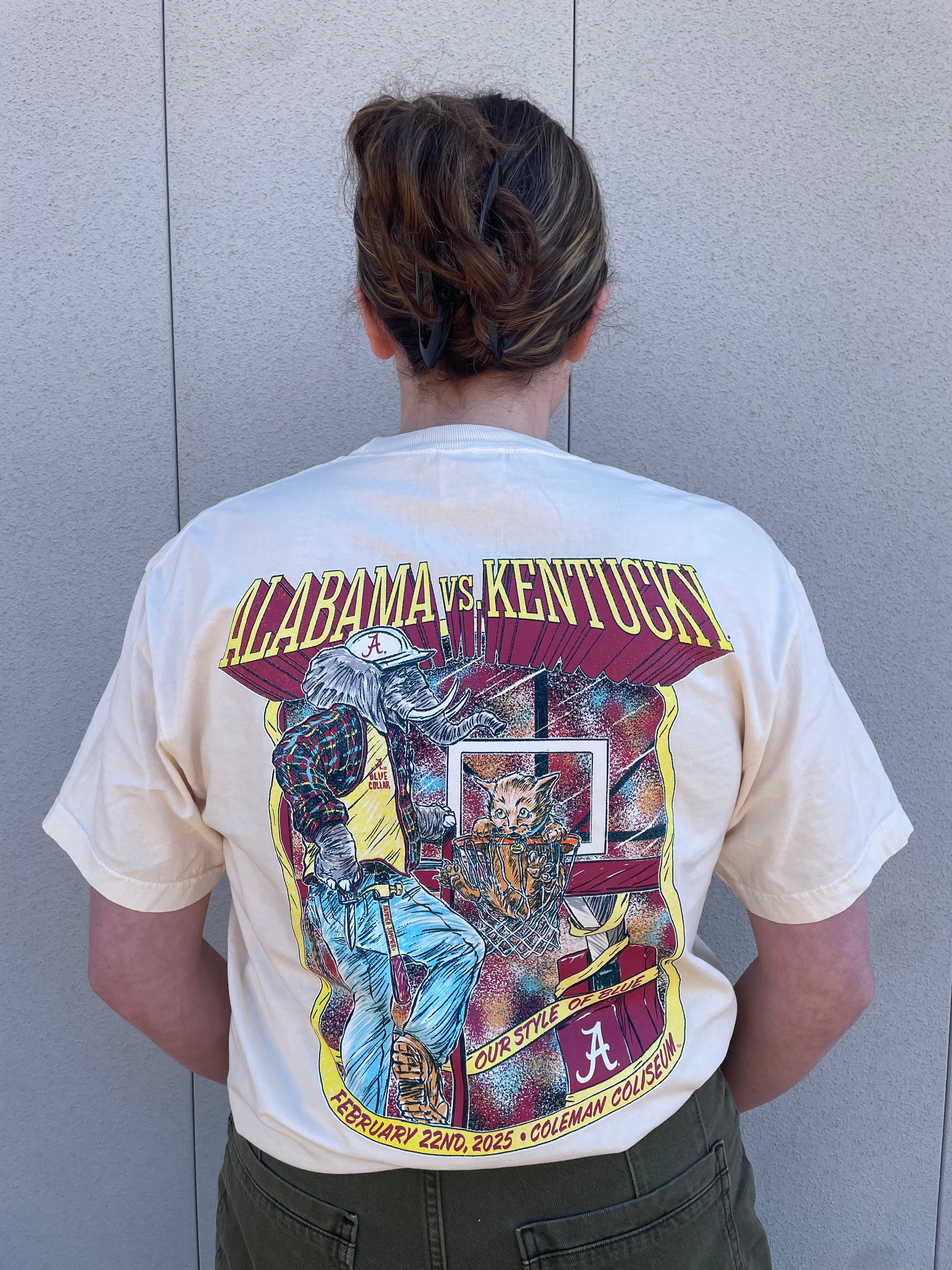 University of Alabama Alabama vs. Kentucky Basketball 2025 Ivory  Comfort Colors T-Shirt with Yellow text "Alabama vs. Kentucky" and an image of Big Al putting the Kentucky Wildcat into the Basketball Hoop