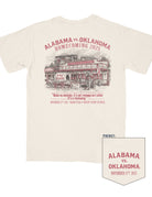 University of Alabama Ivory Shirt with Red text “Alabama vs. Oklahoma Homecoming 2025” above an illustration of an old west style general store with a cart outside painted with “See Ya Sooners!” in Red paint