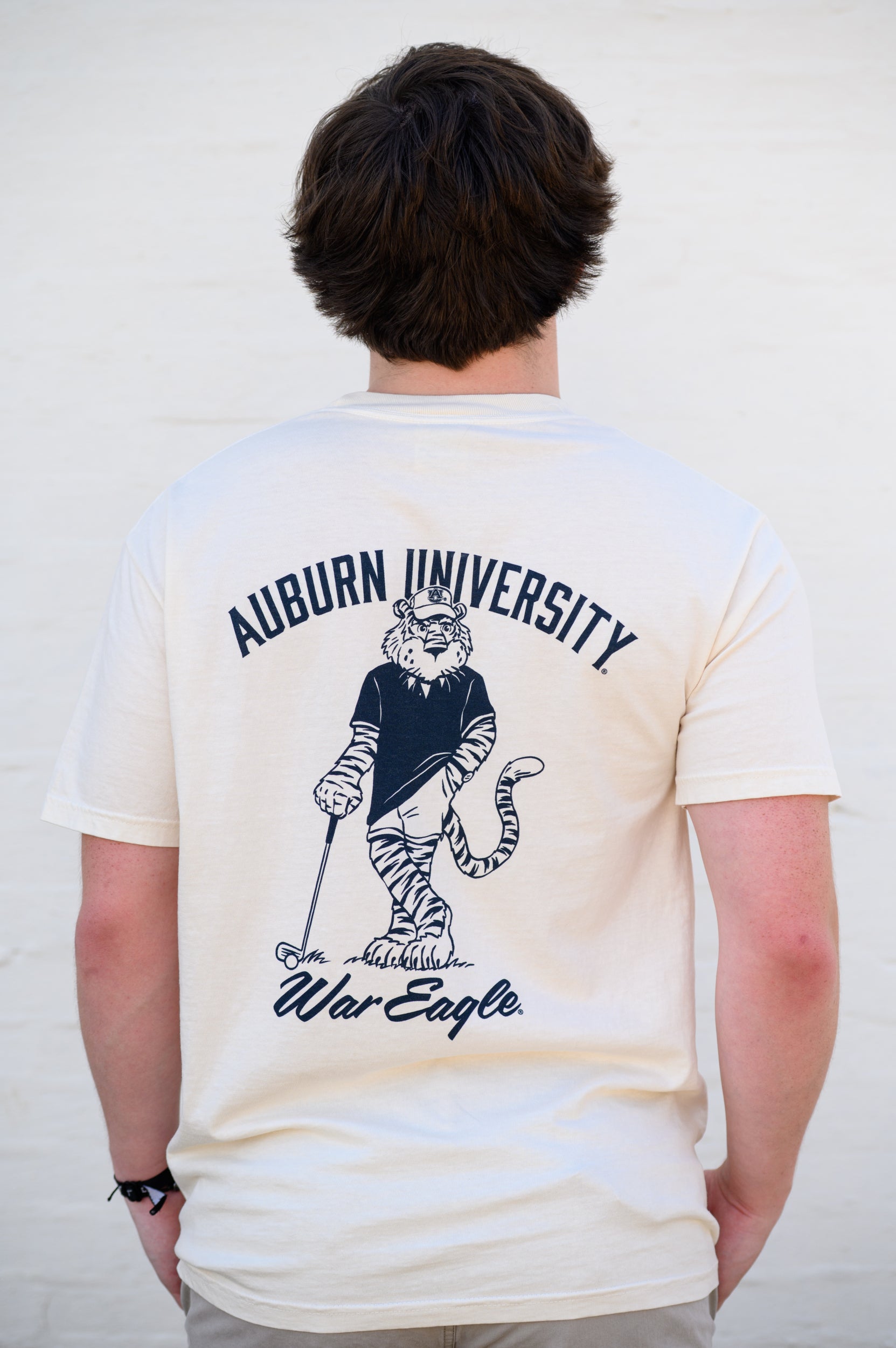 Auburn University Ivory T-Shirt with an image of Aubie leaning against a golf club between Navy Text "Auburn University" and "War Eagle"