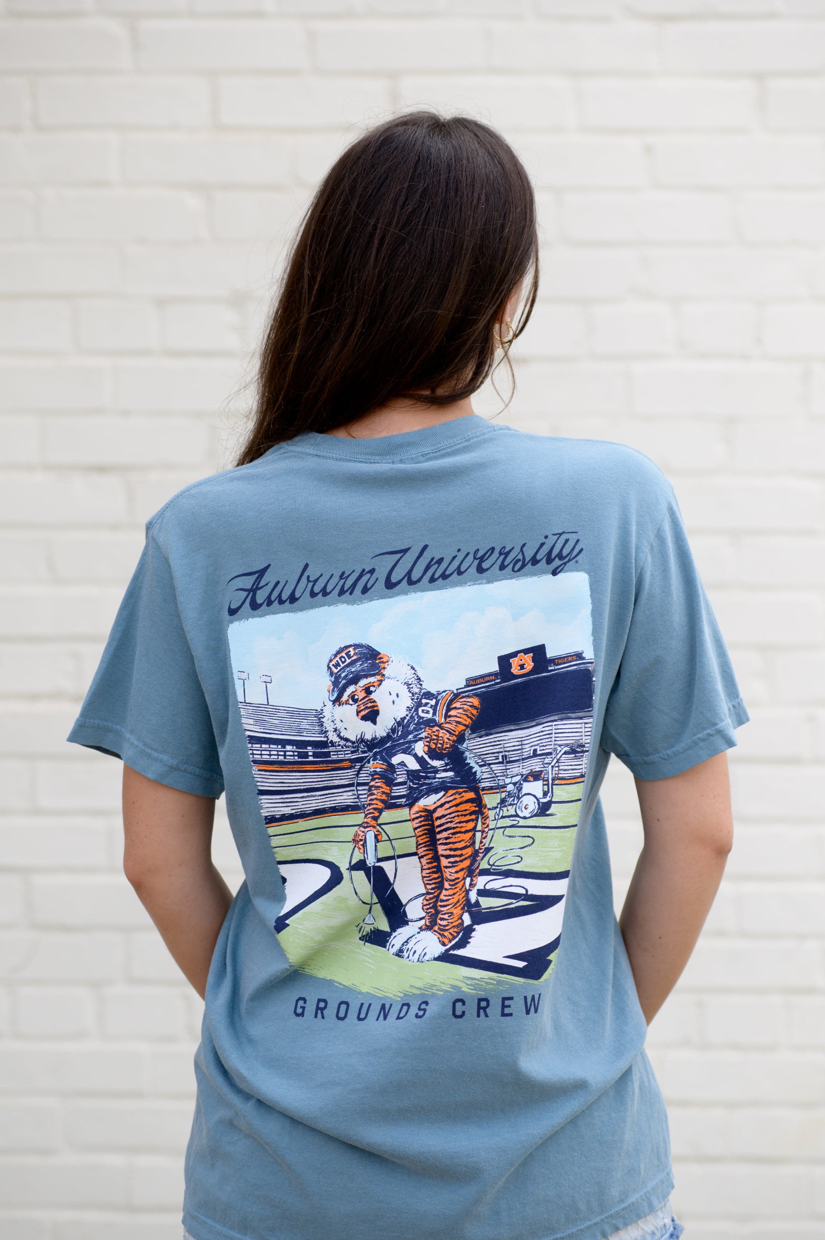Auburn University Aubie Grounds Crew Ice Blue Comfort Colors T-Shirt with an image of Aubie the Tiger wearing a hat and painting the turf on the football field