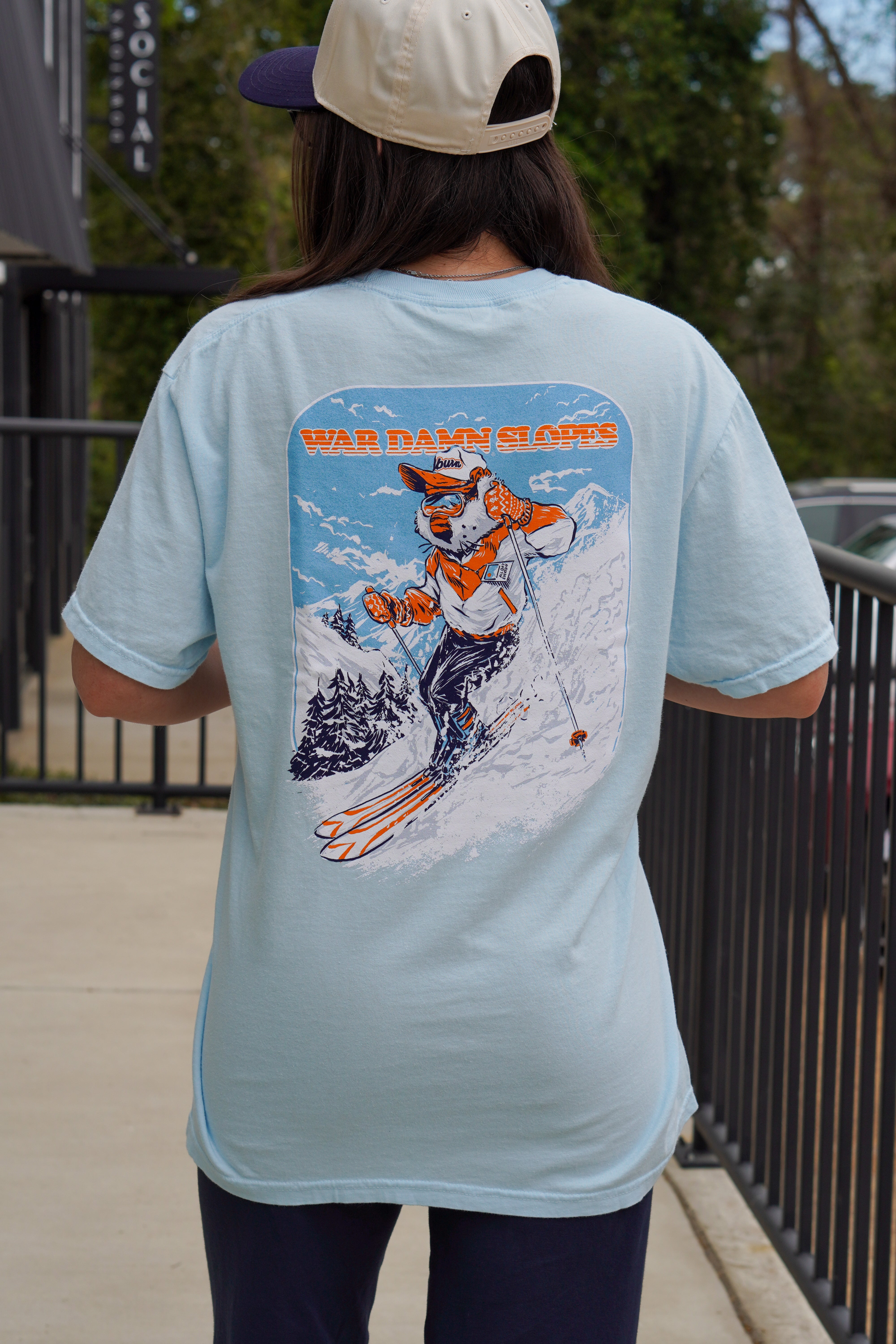 Auburn University Aubie Snow Skiing Chambray Comfort Colors T-Shirt with text "War Damn Slopes" above an image of Aubie in a ski outfit skiing down a snow-covered mountain 