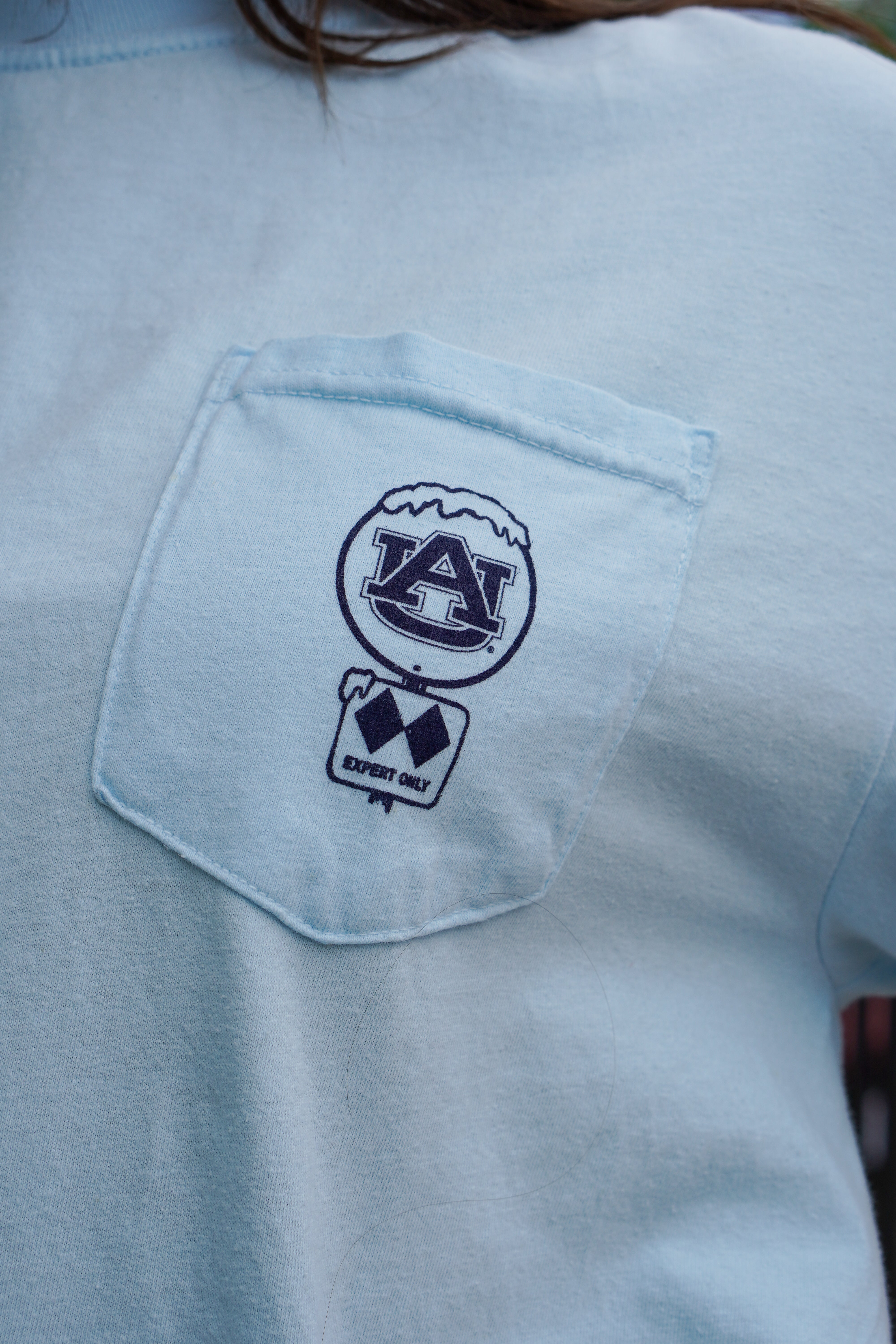 Auburn University Aubie Snow Skiing Chambray Comfort Colors T-Shirt with text "War Damn Slopes" above an image of Aubie in a ski outfit skiing down a snow-covered mountain 