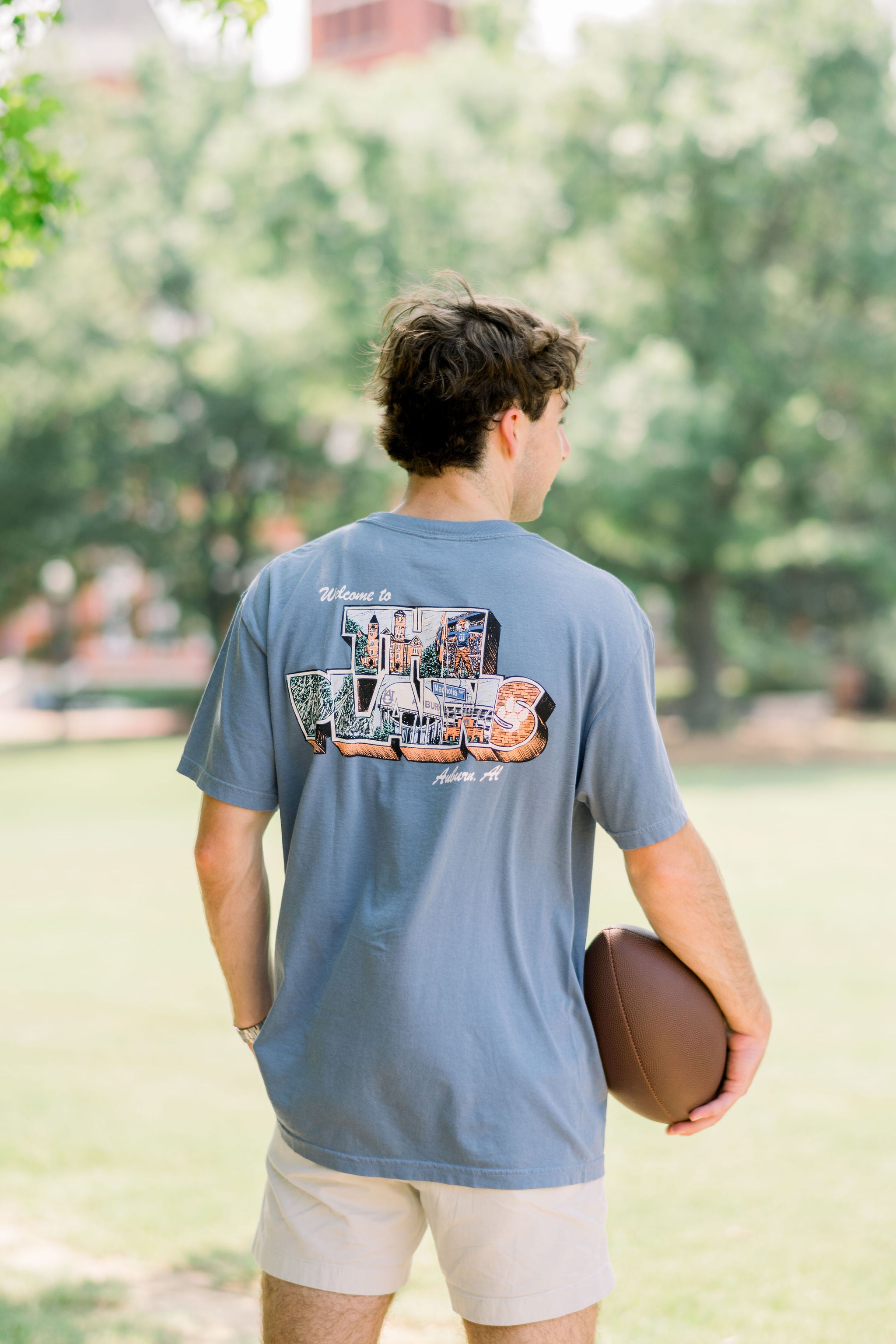 Auburn University Blue The Plains T-Shirt with postcard style text "Welcome to THE PLAINS" with "The Plains" filled with images of iconic buildings in that location