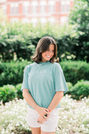 Auburn University Dark Teal T-Shirt with Light Blue Text “Auburn” on the front, and Light Blue sketches of Toomers Tree, Neville Arena, Jordan Hare Stadium, and Sanford Hall on the back