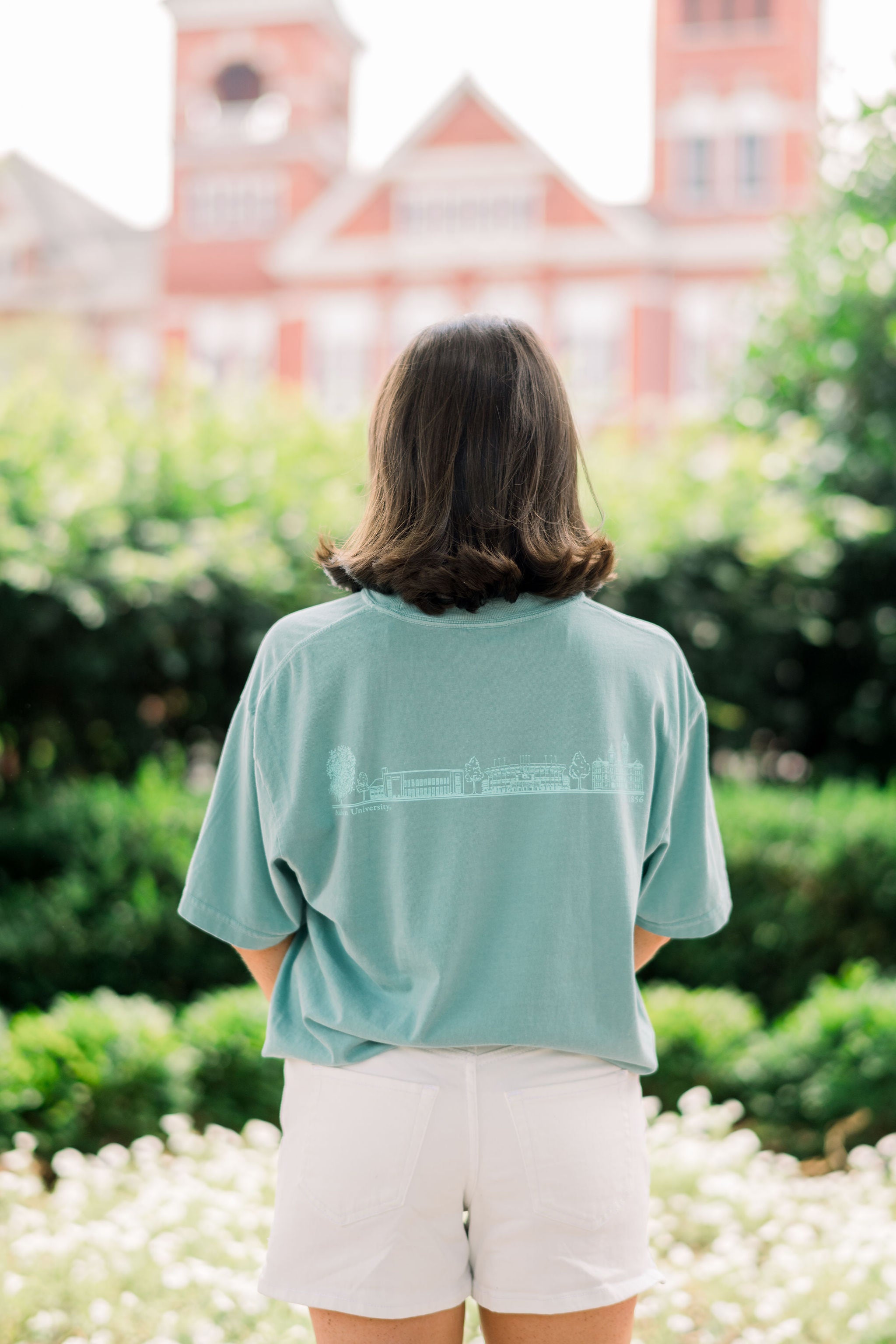 Auburn University Dark Teal T-Shirt with Light Blue Text “Auburn” on the front, and Light Blue sketches of Toomers Tree, Neville Arena, Jordan Hare Stadium, and Sanford Hall on the back