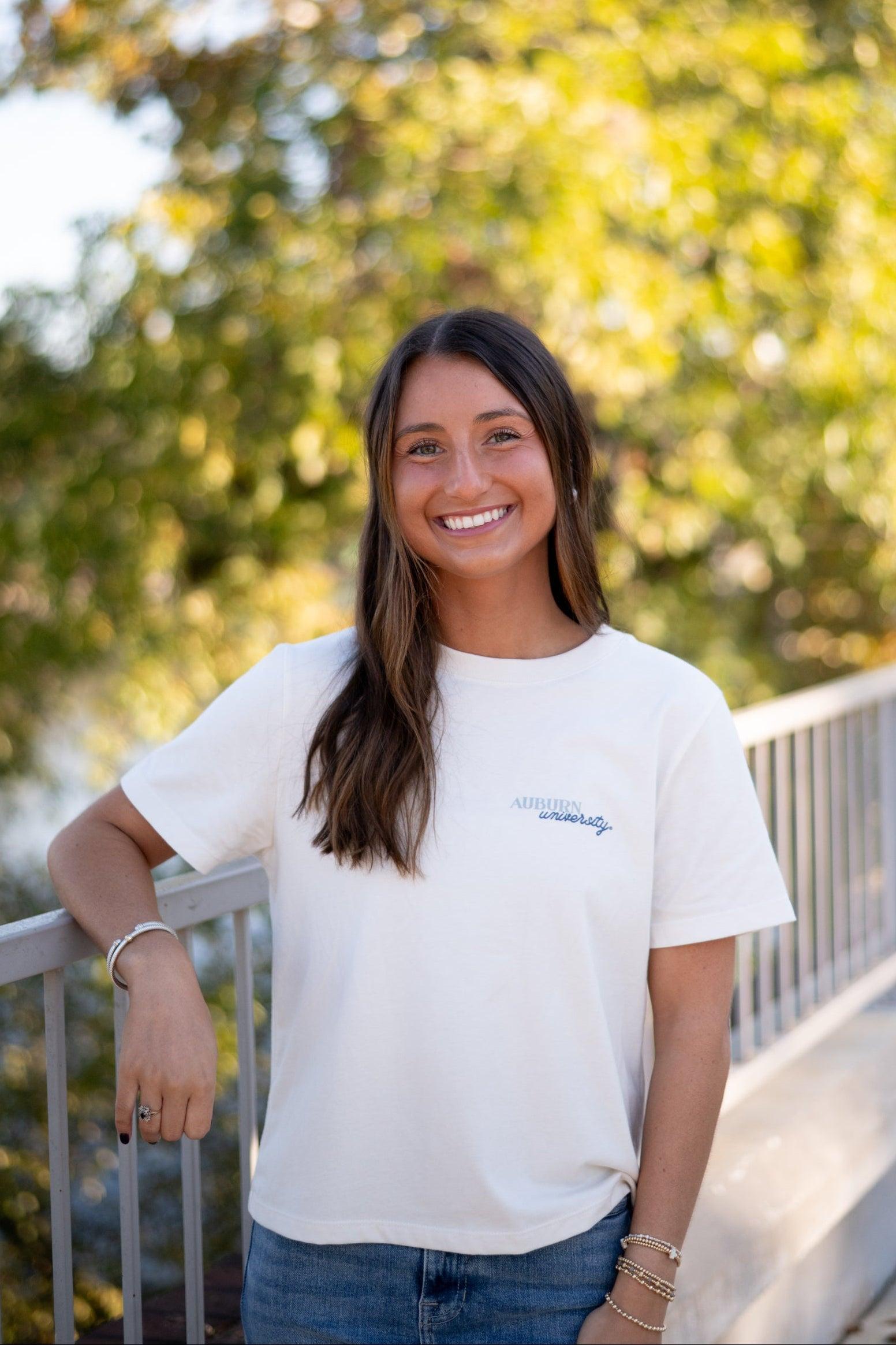 Auburn University White Ladies Tee with a vintage Blue illustration of cowgirl boots with bows tied on them above Blue text “Home On The Plains”