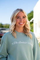 Auburn University Seafoam Crewneck with cursive writing on the front and an open locket with the writing “WDE” inside on the back