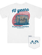 Avenue Pub 10 Year Anniversary White Comfort Colors T-Shirt with text "10 years" and "And we're STILL not tapped out" above a graphic of a tapped barrel (Back) | Avenue Pub Logo  on pocket (Front)