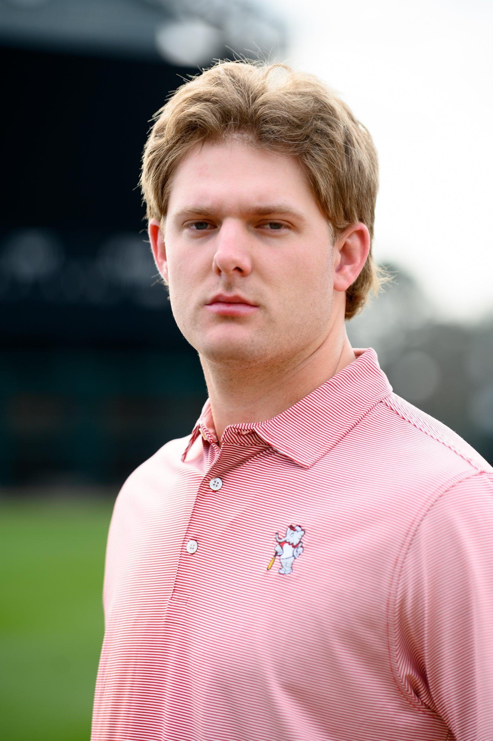 University of Alabama Men's Crimson Stripe Performance Polo with an embroidered image of Big Al in a baseball uniform leaning on a baseball bat