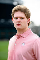 University of Alabama Men's Crimson Stripe Performance Polo with an embroidered image of Big Al in a baseball uniform leaning on a baseball bat