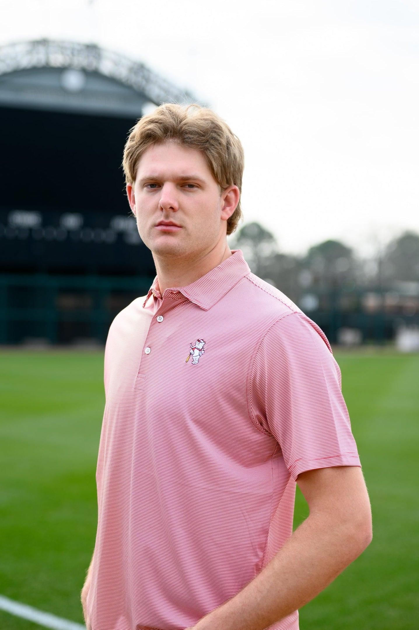 University of Alabama Men's Crimson Stripe Performance Polo with an embroidered image of Big Al in a baseball uniform leaning on a baseball bat