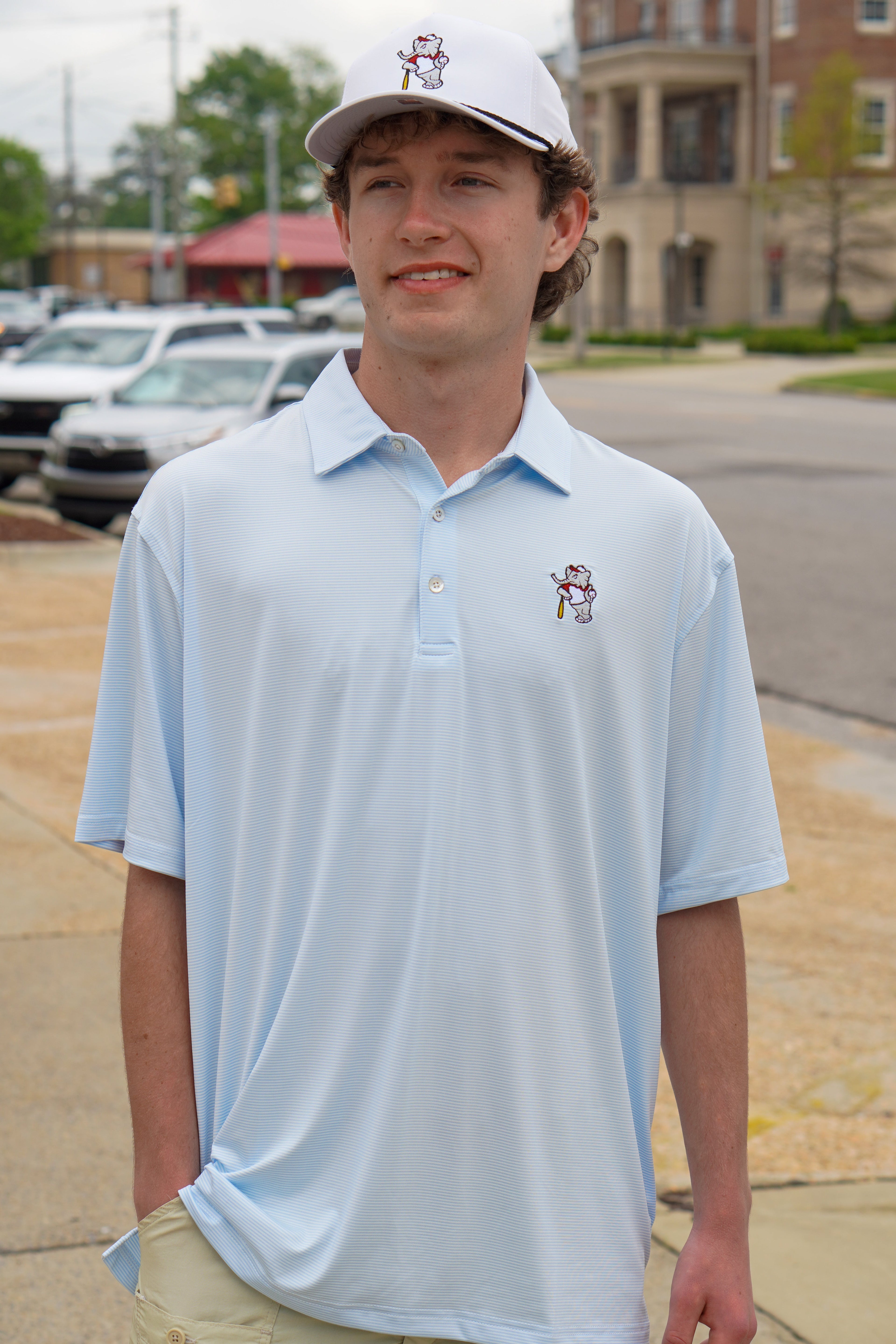 University of Alabama BallPlayer Al Men's Light Blue Performance Polo with an embroidered image of Big Al in a baseball uniform leaning on a baseball bat