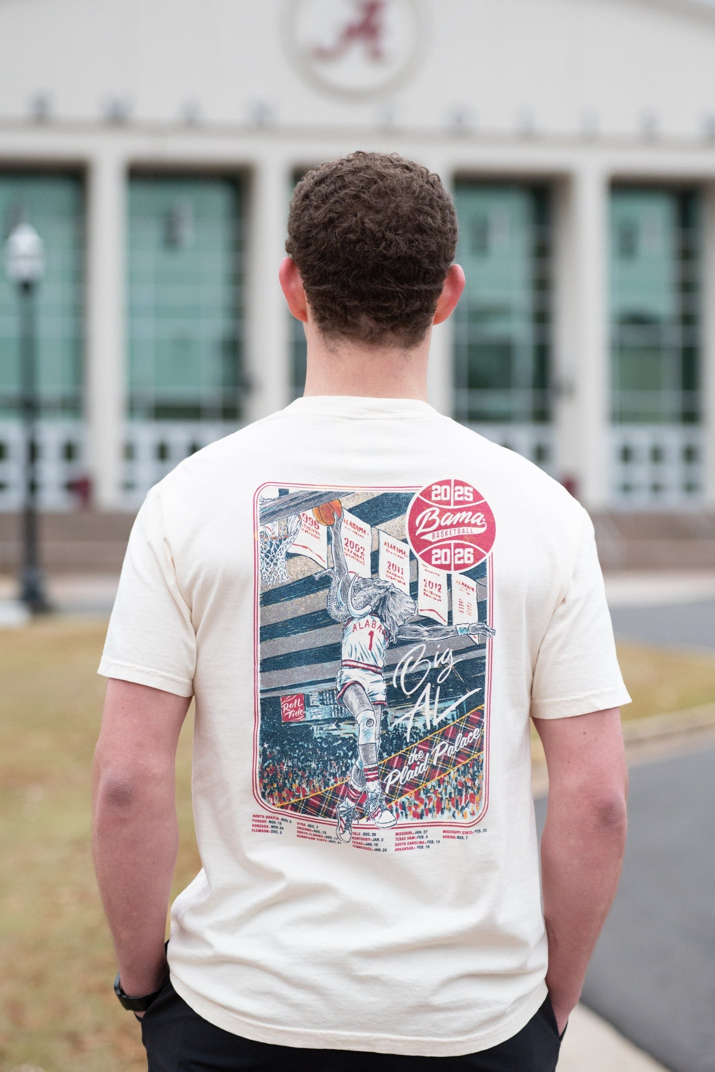 University of Alabama Ivory Shirt with an illustration of Big Al dunking a basketball next to text “Big Al” and “the Plaid Palace” above the 2025 Basketball Schedule