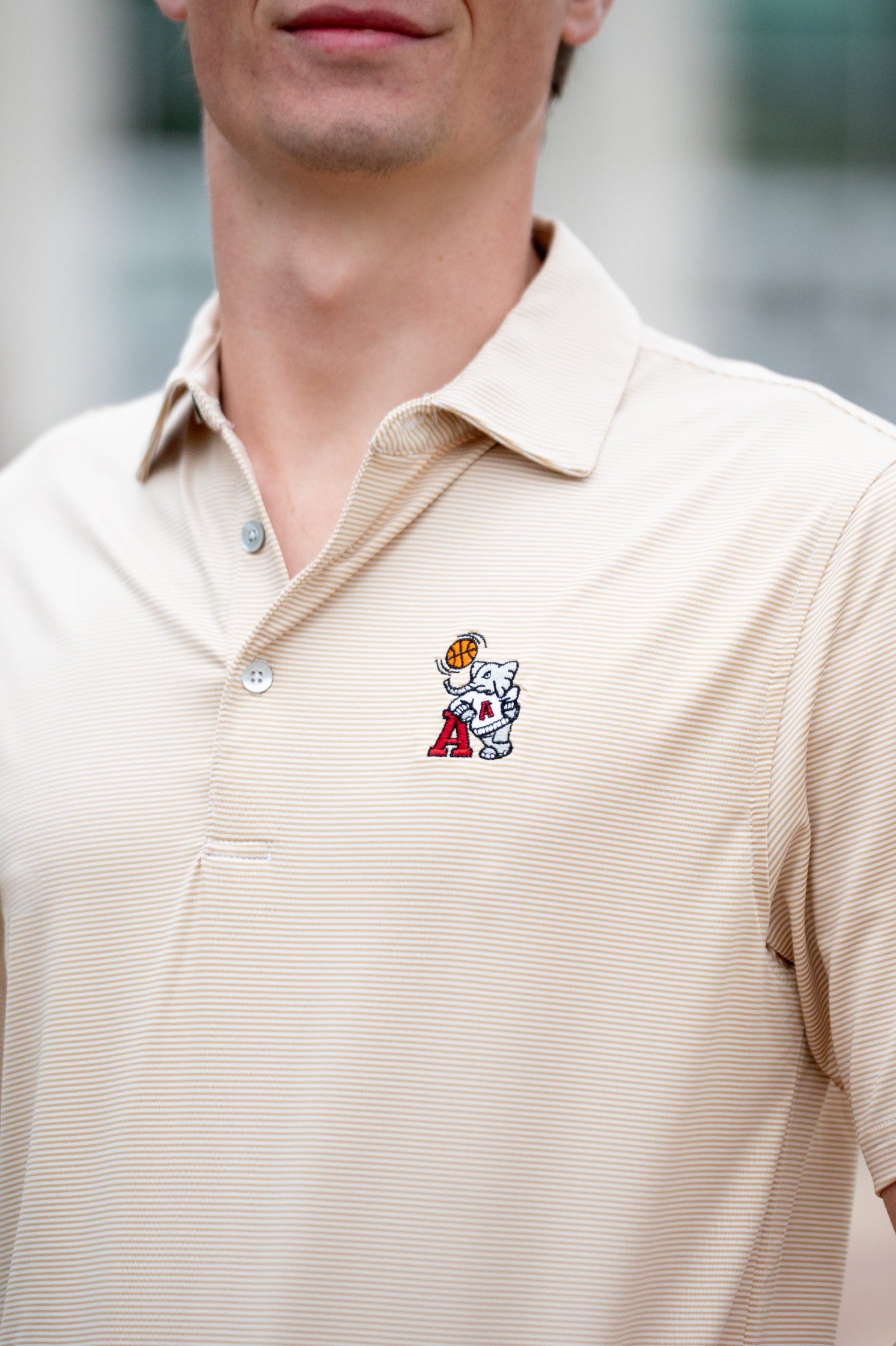 University of Alabama Basketball Al Tan Men’s Polo with an embroidered Big Al in a sweater holding a basketball and leaning against an "A"