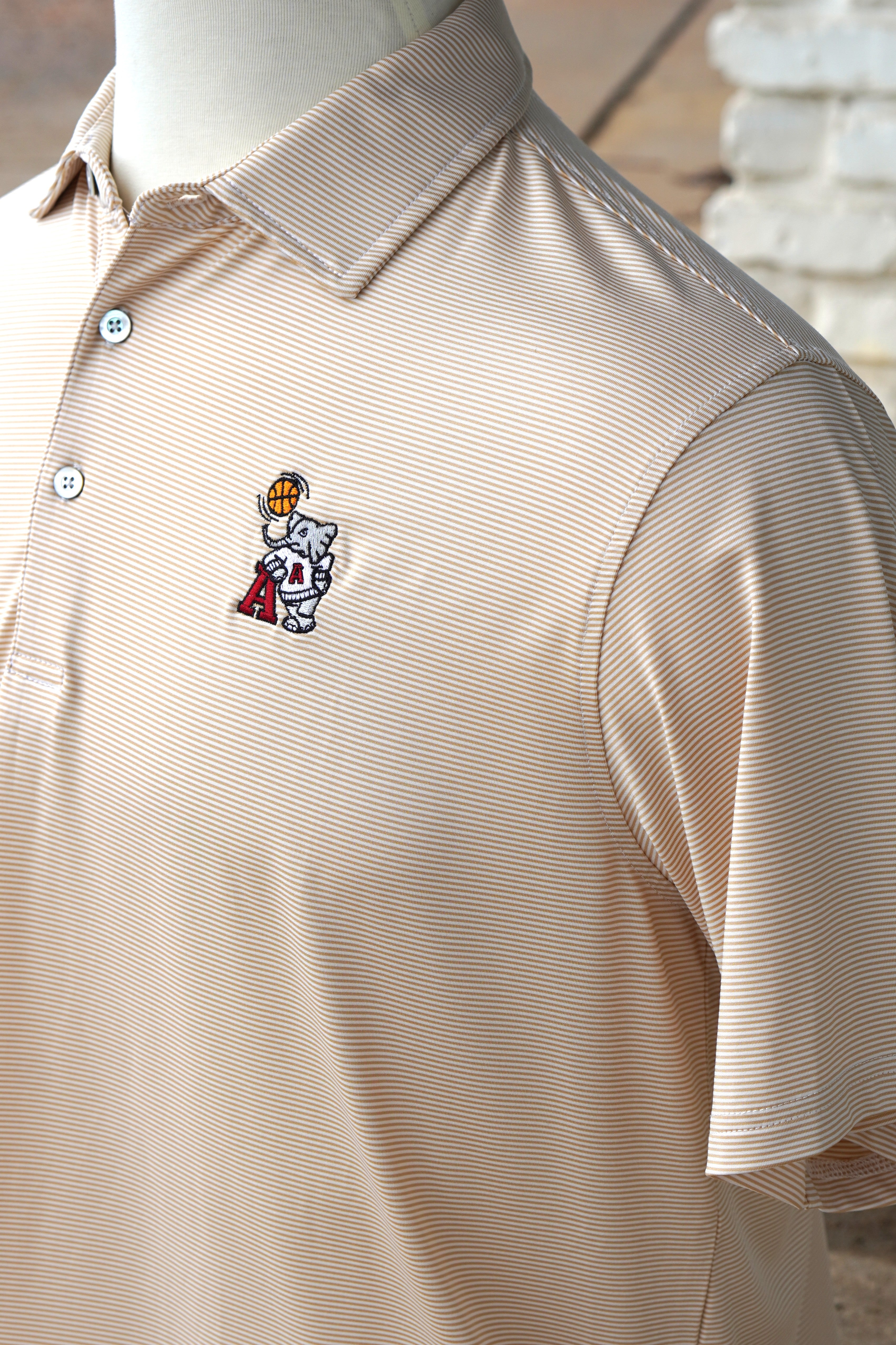 University of Alabama Basketball Al Tan Men’s Polo with an embroidered Big Al in a sweater holding a basketball and leaning against an "A"