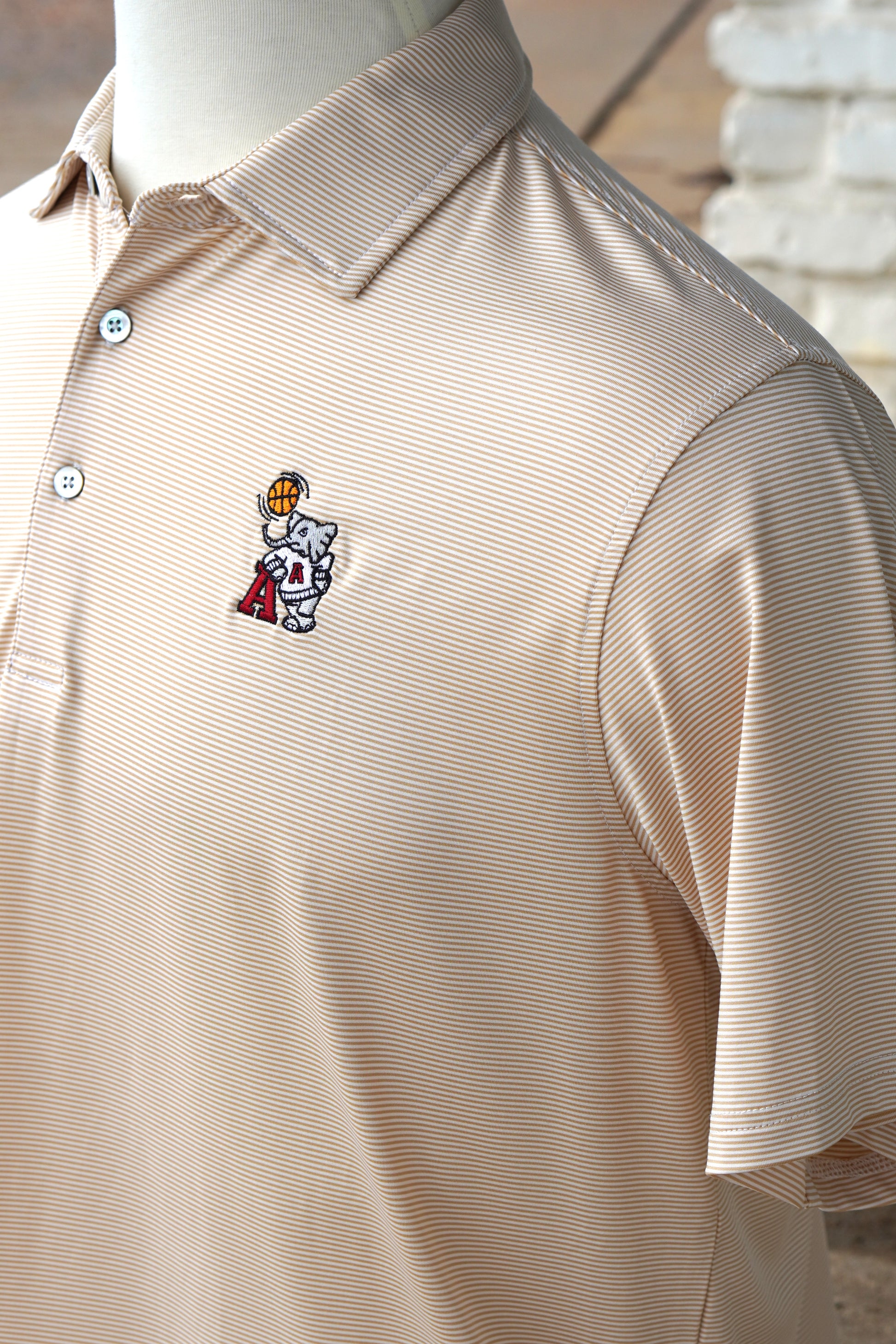 University of Alabama Basketball Al Tan Men’s Polo with an embroidered Big Al in a sweater holding a basketball and leaning against an "A"