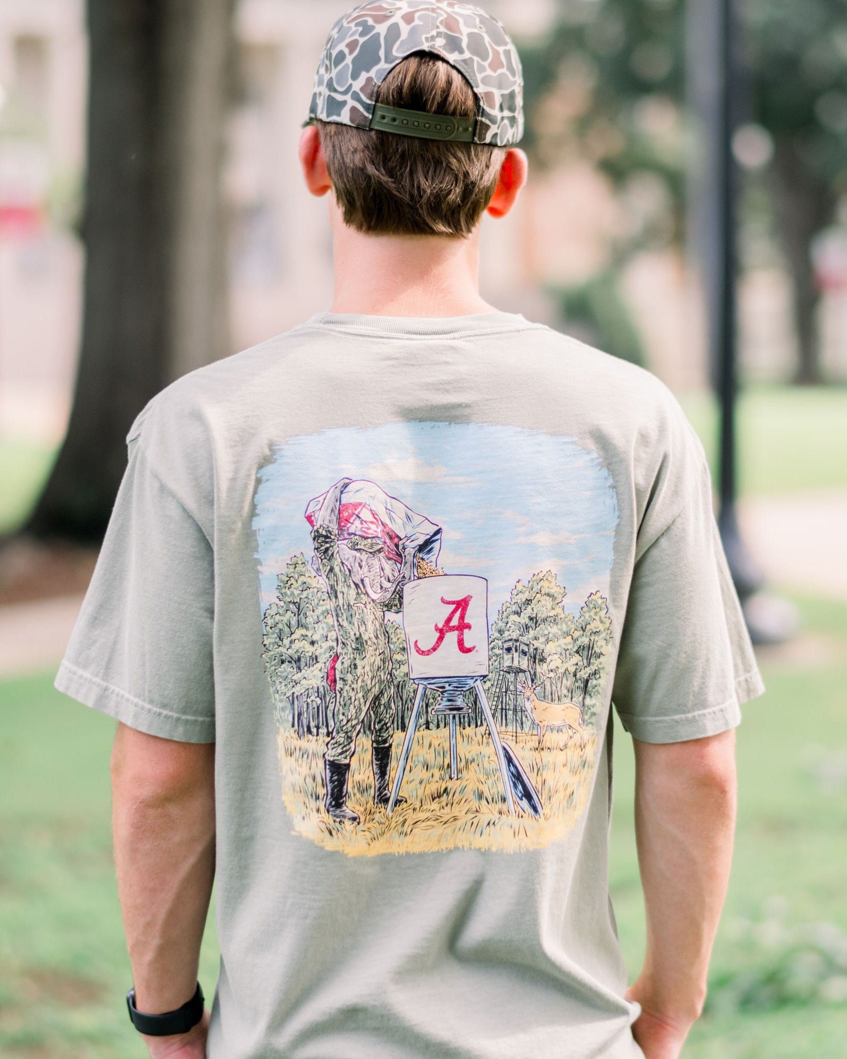 University of Alabama Sandstone T-Shirt with an illustration of Big Al in hunting gear filling a Script A deer feeder with a deer in the background