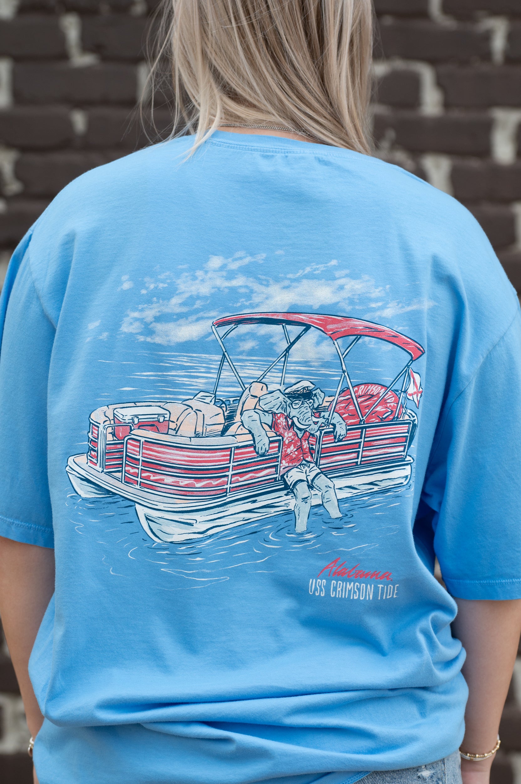 University of Alabama Big Al Pontoon Azure Comfort Colors T-Shirt with an image of Big Al lounging on the side of a Red and White Pontoon Boat  with the text "USS Crimson Tide" below