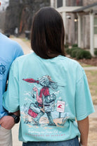 University of Alabama Mint T-Shirt with an image of Big Al in beach clothes carrying an umbrella dragging a cooler across the sand